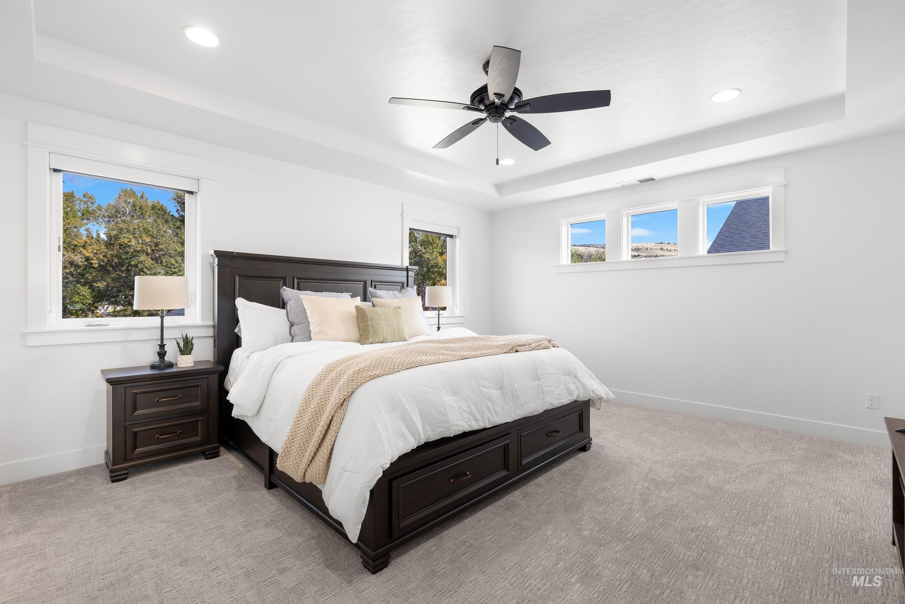 Bedroom featuring a tray ceiling, light carpet, a ceiling fan, and recessed lighting