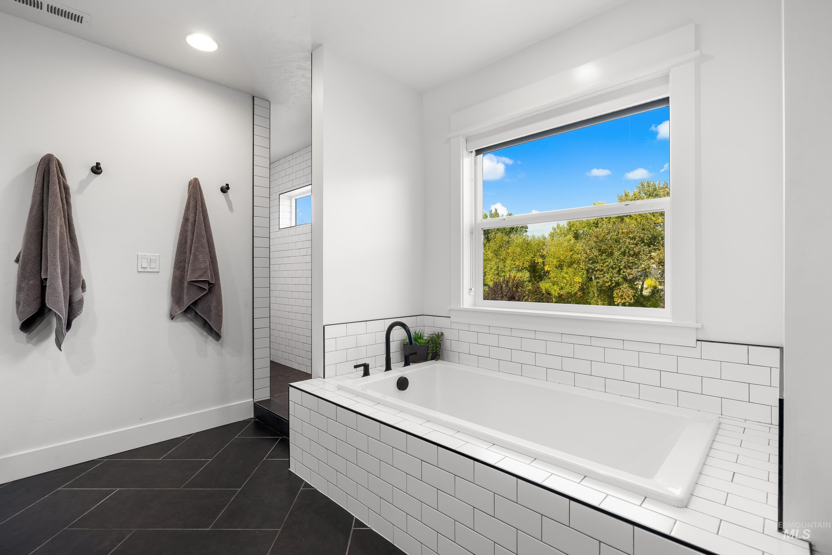 Bathroom with a garden tub, dark tile patterned floors, and recessed lighting