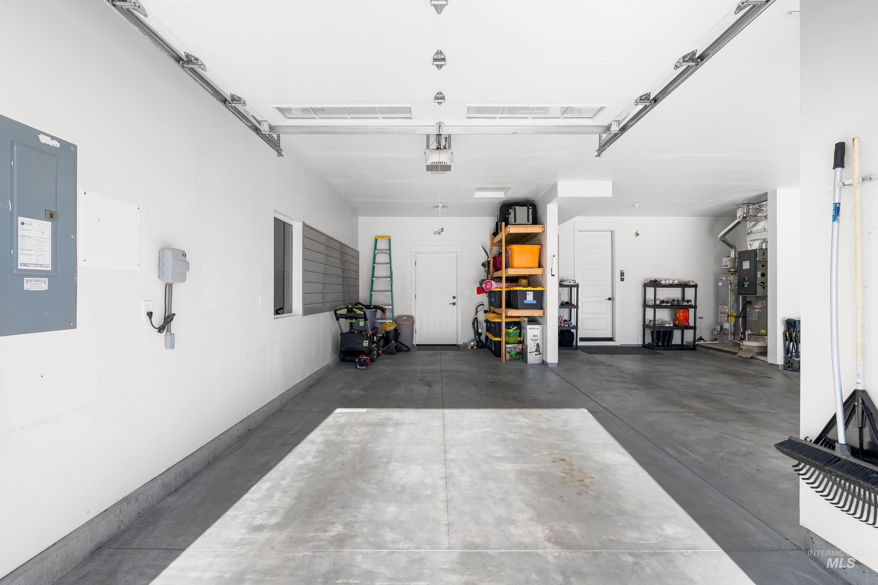 Garage with electric panel, heating unit, and a garage door opener