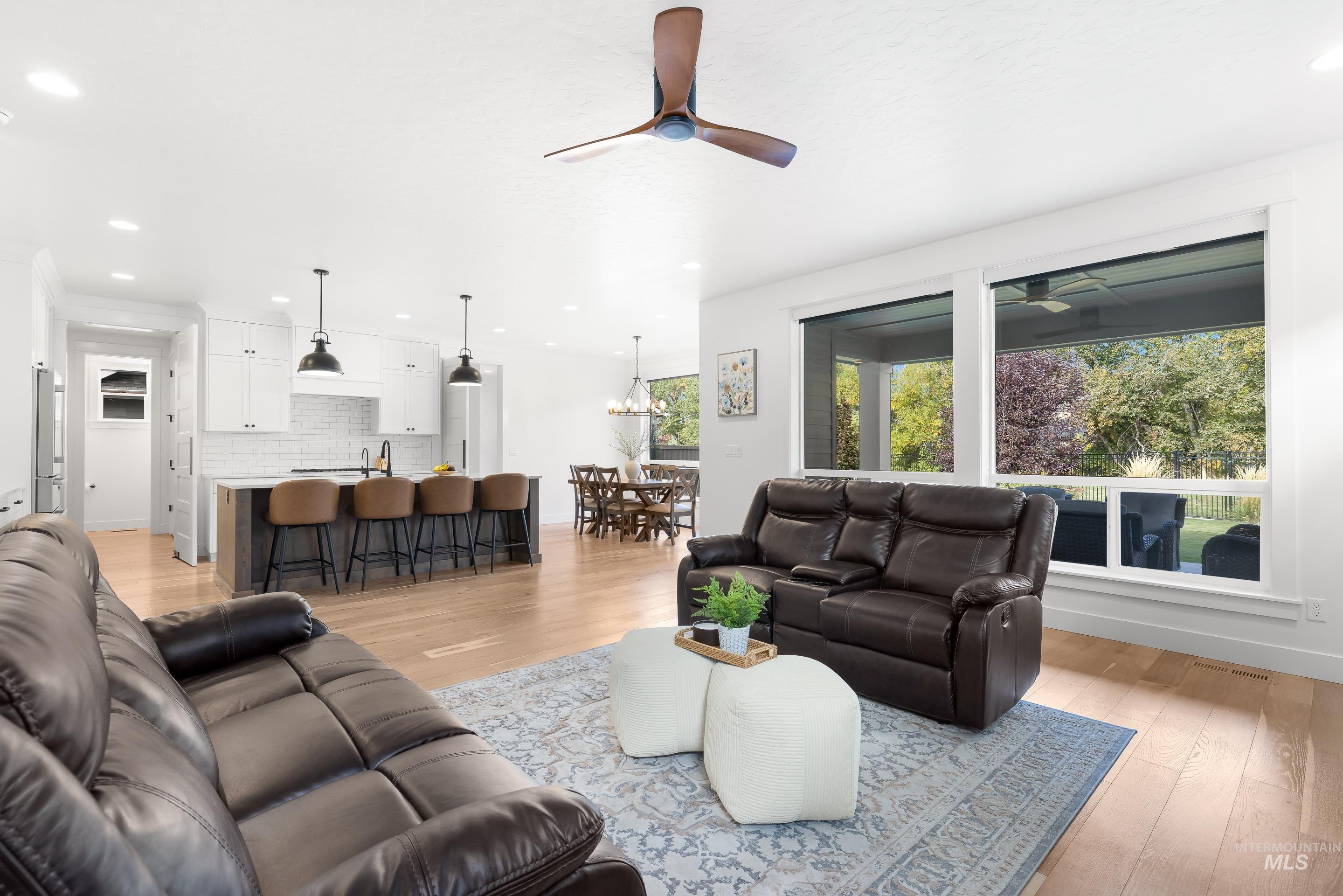 Living room with light wood-style flooring, ceiling fan, recessed lighting, and a chandelier