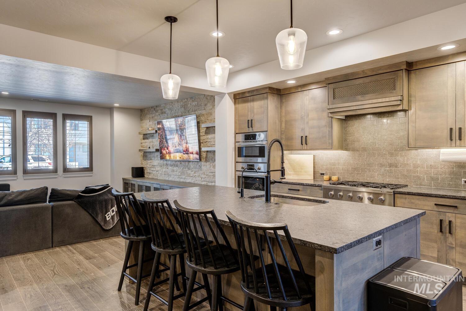 Kitchen with open floor plan, a breakfast bar, hanging light fixtures, an island with sink, and extractor fan