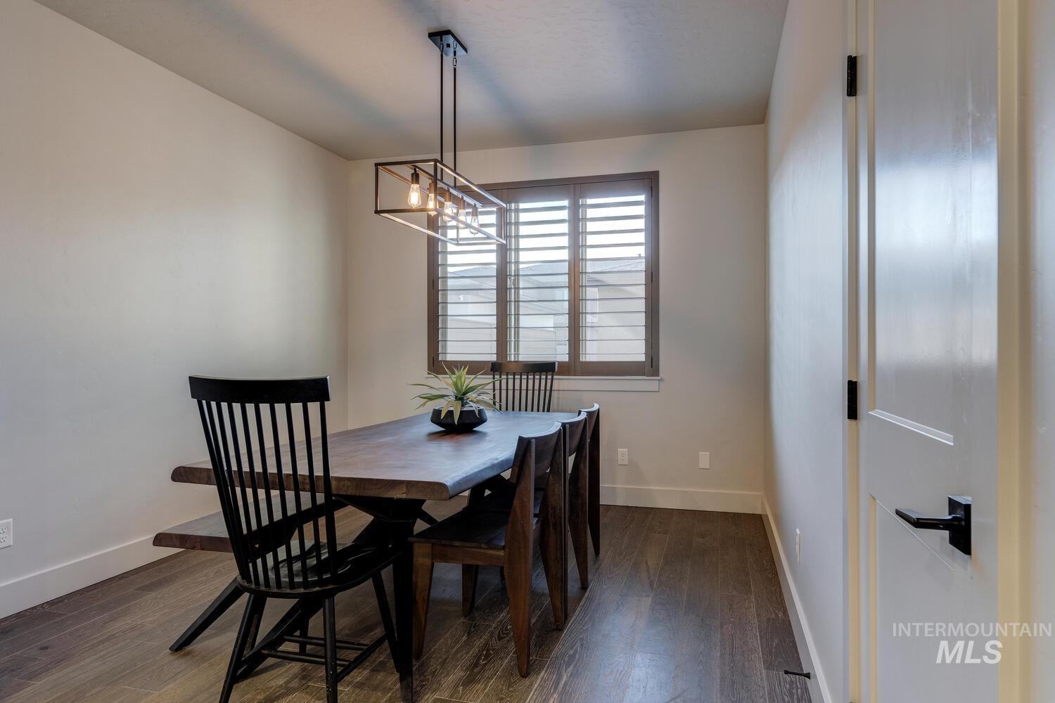 Dining area with dark wood-style flooring and a chandelier
