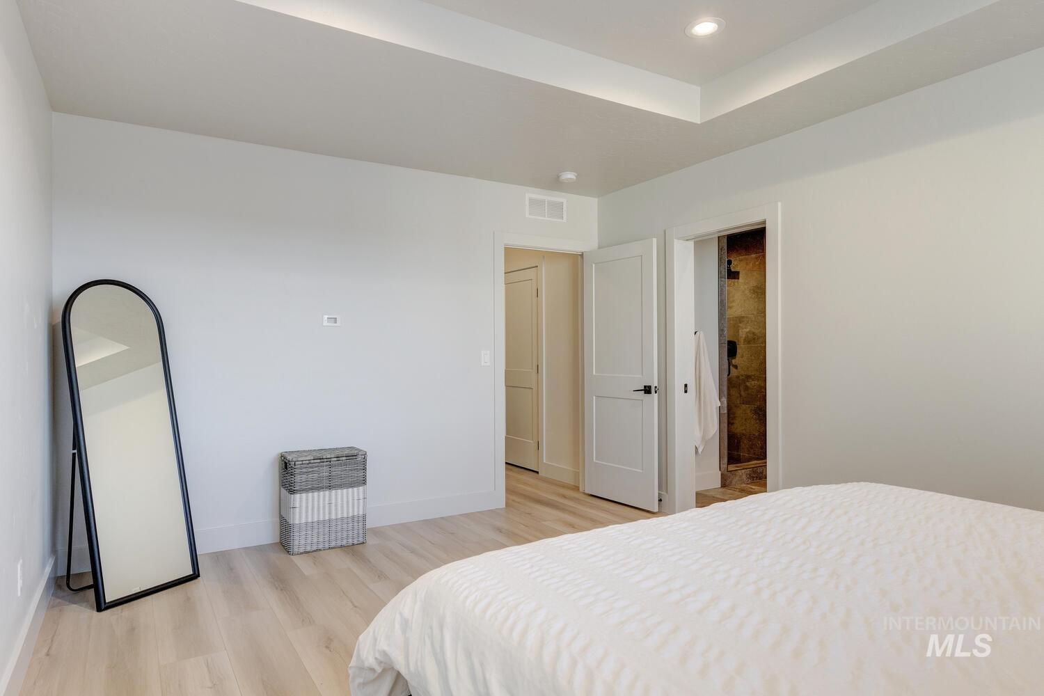 Bedroom featuring light wood-style flooring, ensuite bath, and recessed lighting
