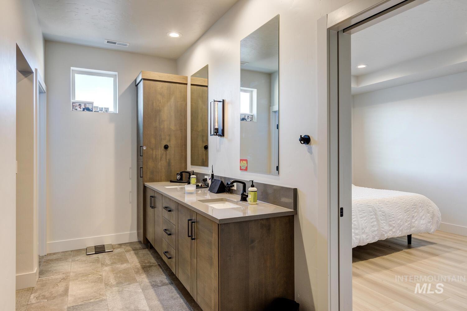Ensuite bathroom featuring double vanity, recessed lighting, and a stall shower