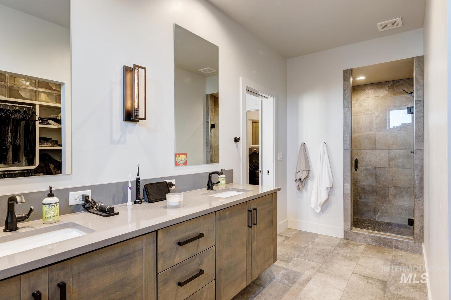 Bathroom with a spacious closet, double vanity, and a stall shower