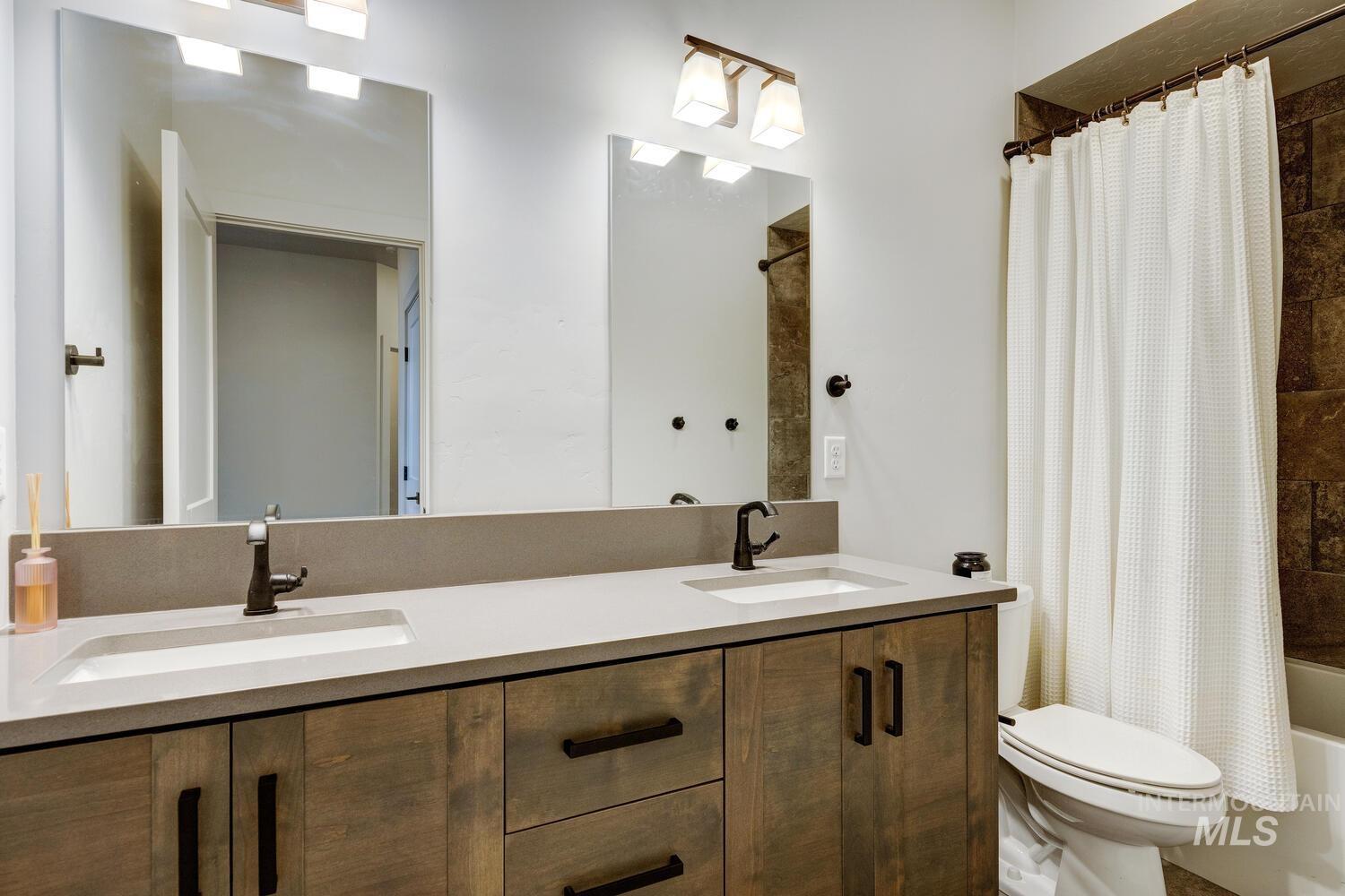 Bathroom featuring shower / tub combo with curtain and double vanity
