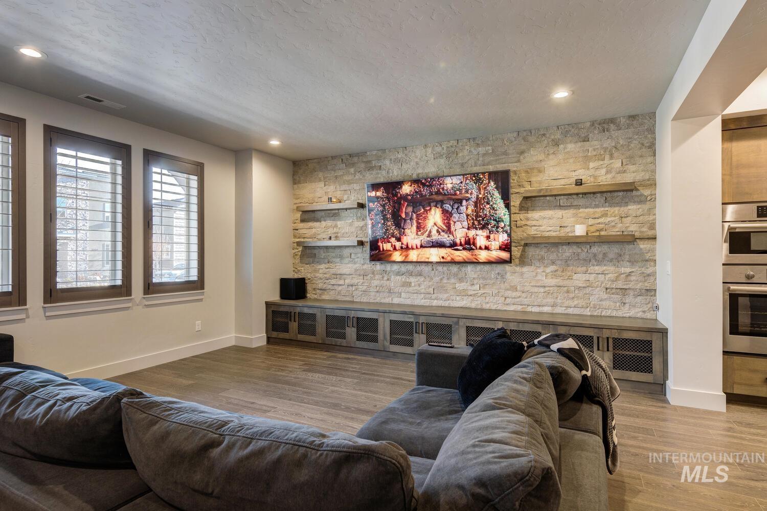 Living area featuring wood finished floors, a textured ceiling, recessed lighting, and an accent wall