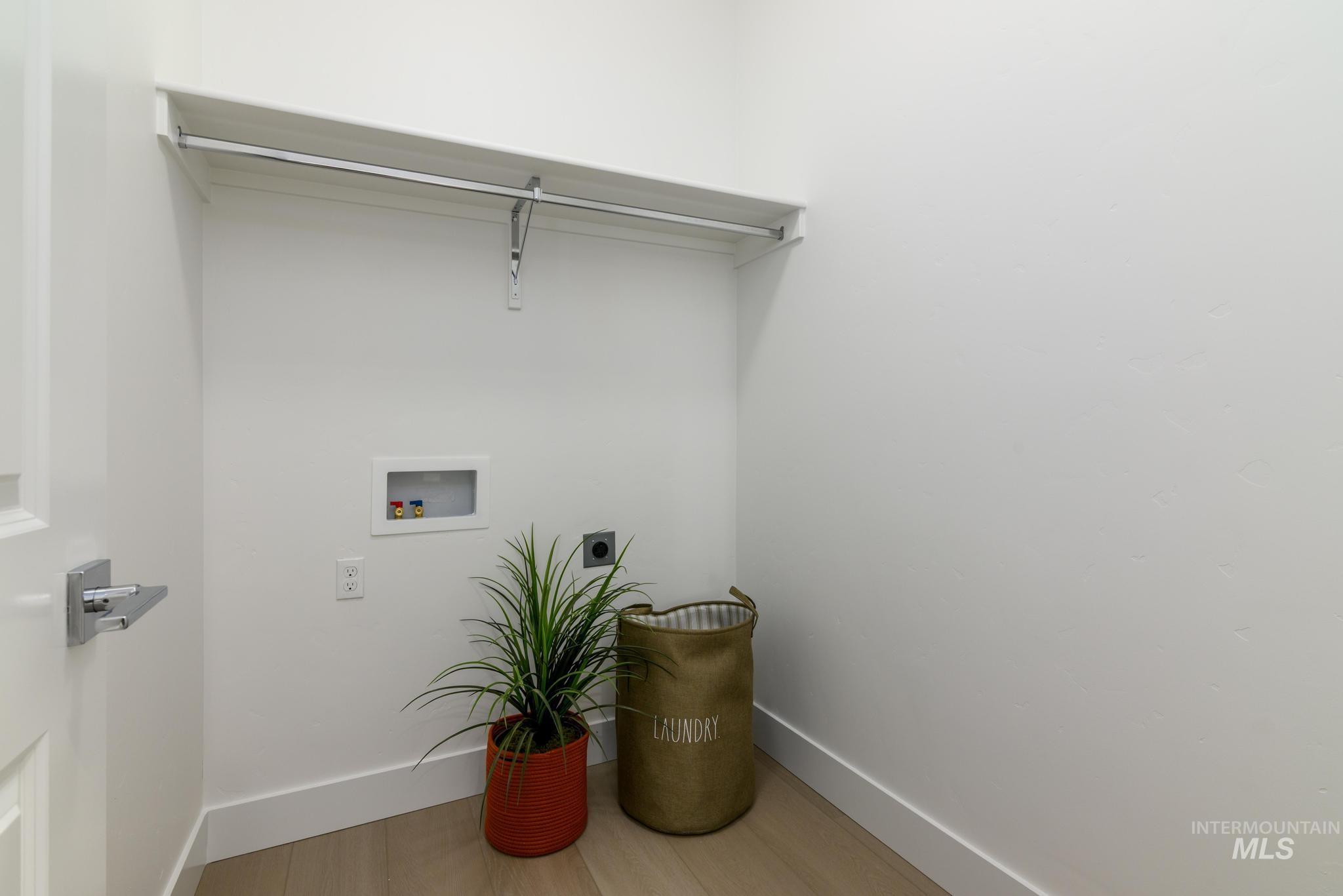 Washroom with electric dryer hookup, washer hookup, and light wood-type flooring