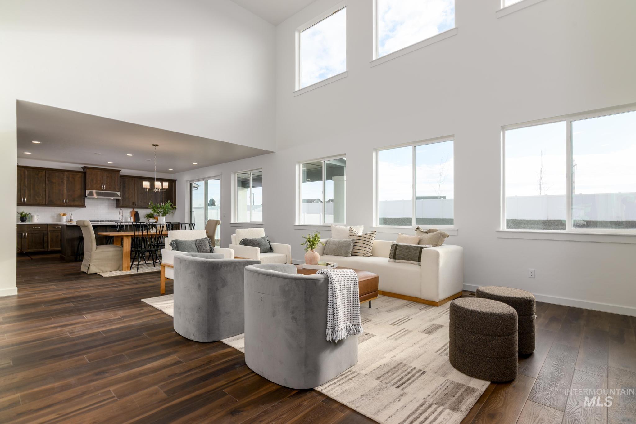 Living room featuring healthy amount of natural light, dark wood-style flooring, a towering ceiling, and recessed lighting