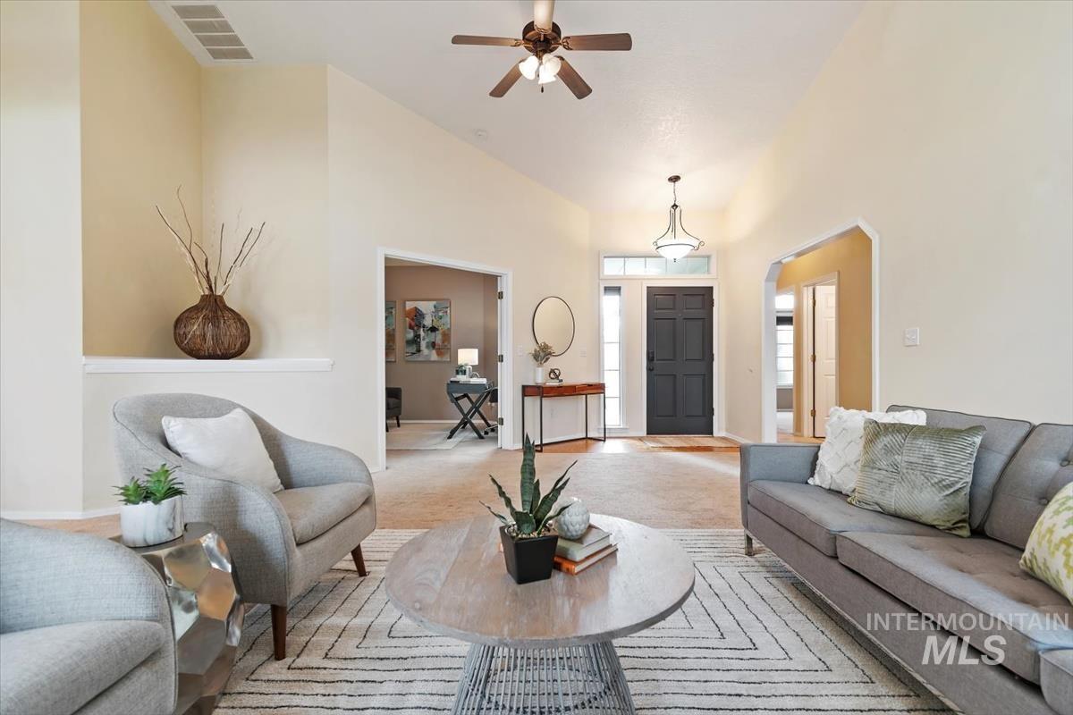 Living room with carpet, high vaulted ceiling, ceiling fan, and arched walkways
