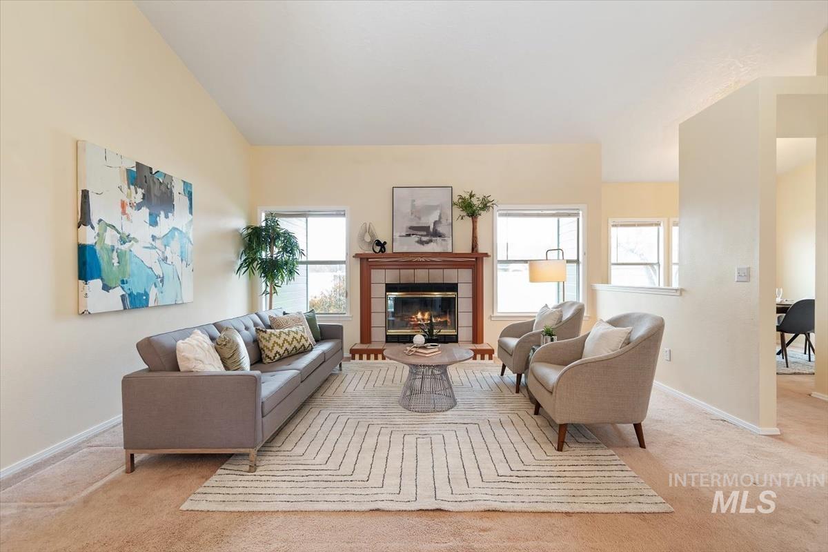 Living room featuring a fireplace, vaulted ceiling, and light carpet