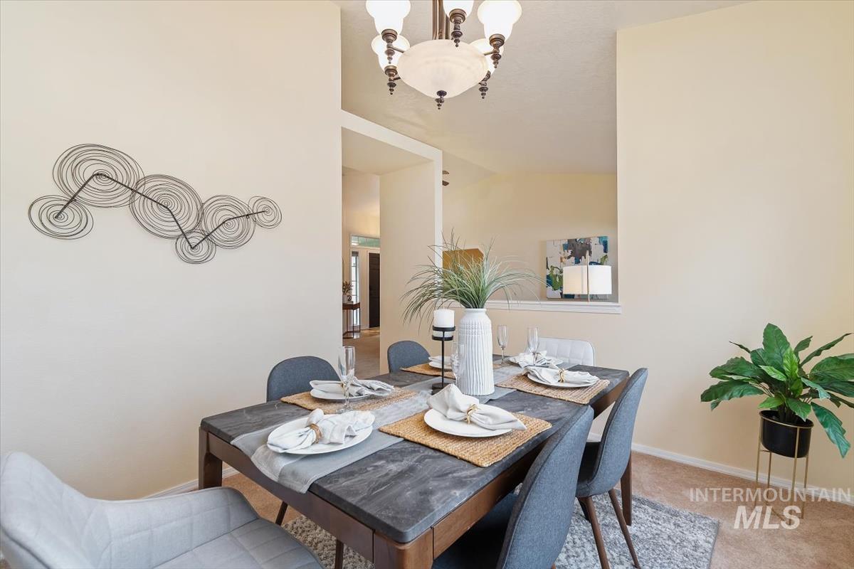 Carpeted dining area featuring a chandelier and vaulted ceiling
