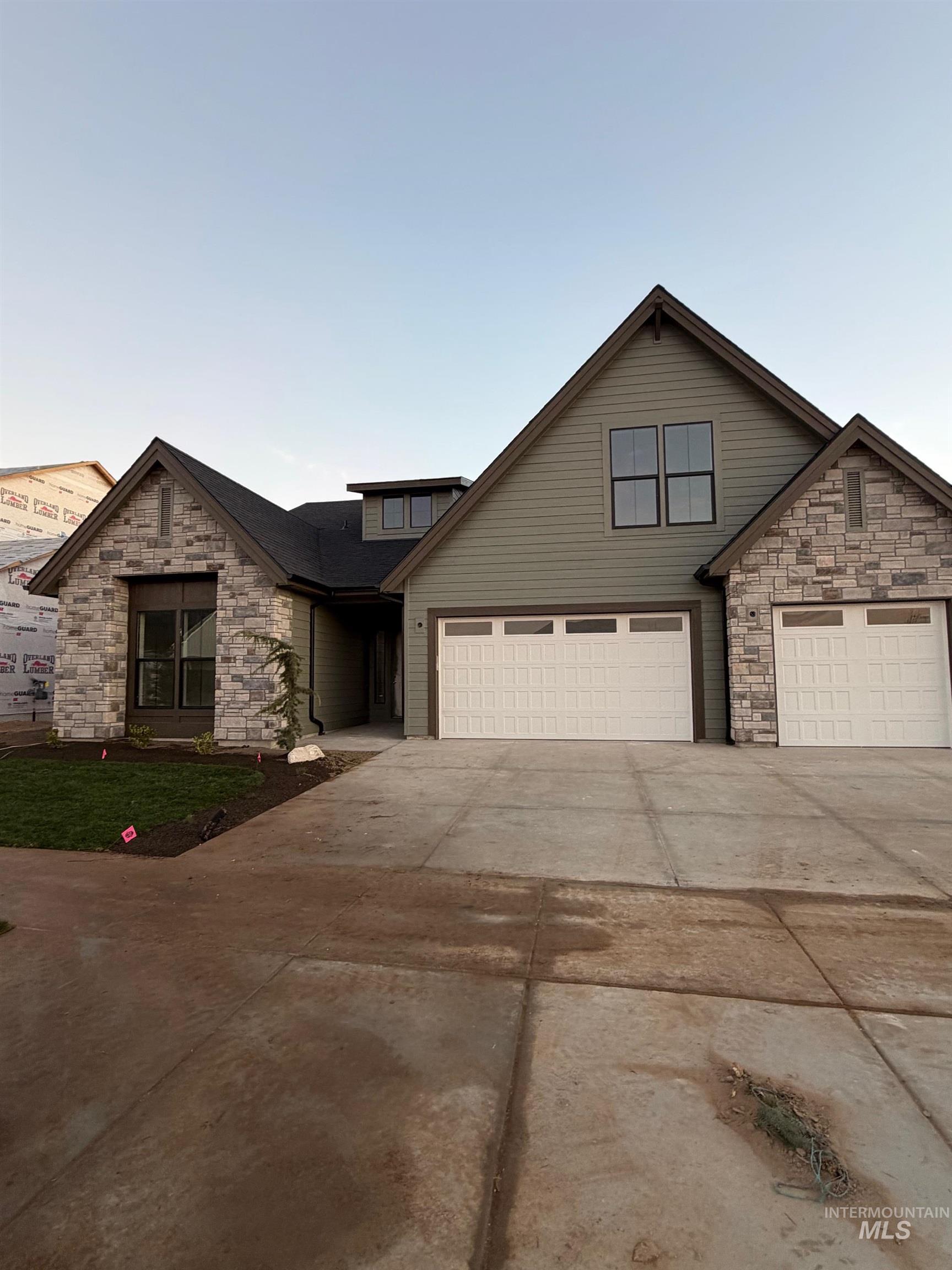 Traditional home featuring stone siding and concrete driveway