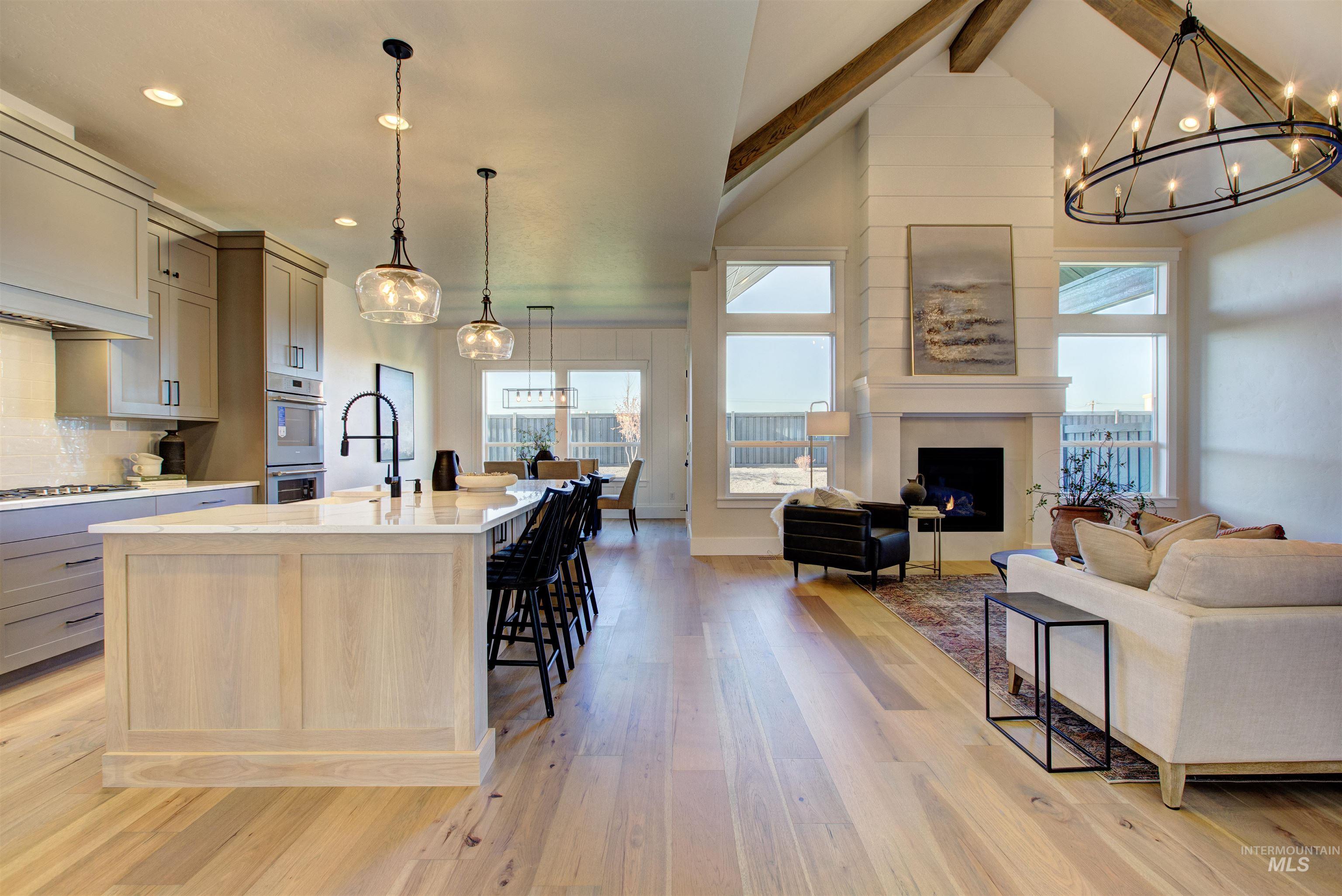 Kitchen featuring a chandelier, open floor plan, beam ceiling, light wood-style floors, and a kitchen breakfast bar