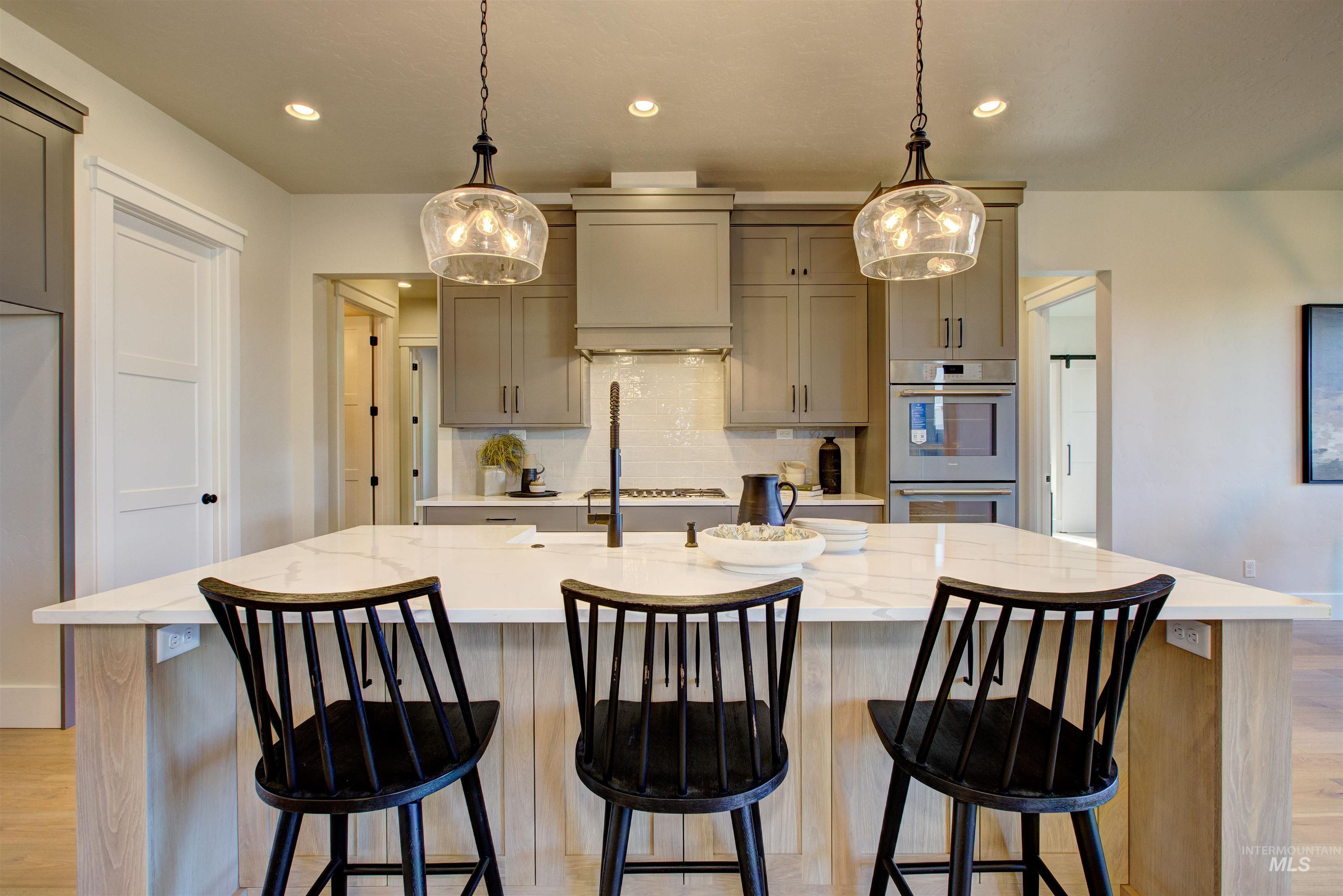 Kitchen featuring decorative backsplash, light wood-style flooring, a kitchen island with sink, light stone countertops, and recessed lighting