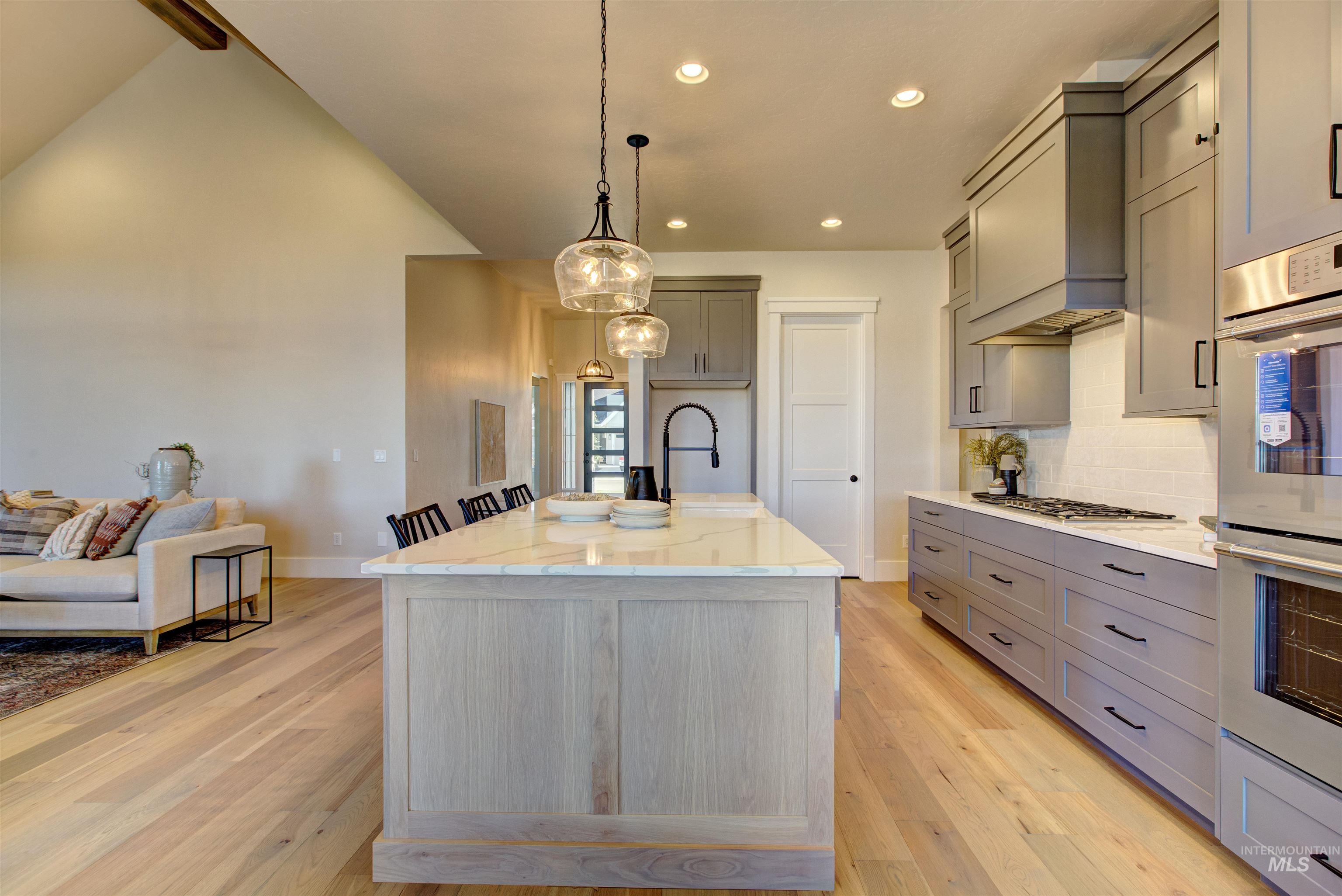 Kitchen with gray cabinets, light stone counters, double oven, decorative backsplash, and recessed lighting