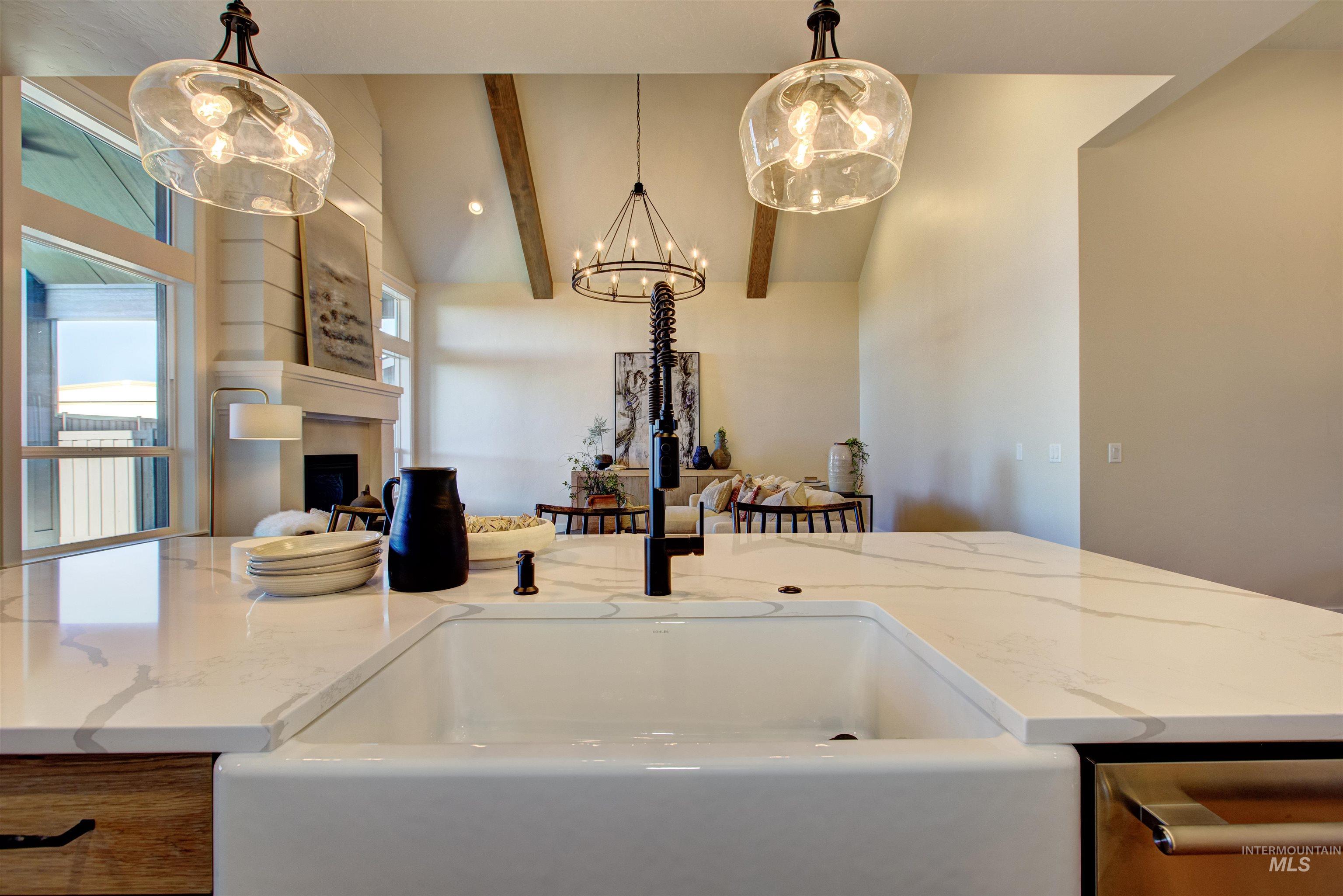 Kitchen featuring light stone counters, a fireplace, pendant lighting, a chandelier, and open floor plan