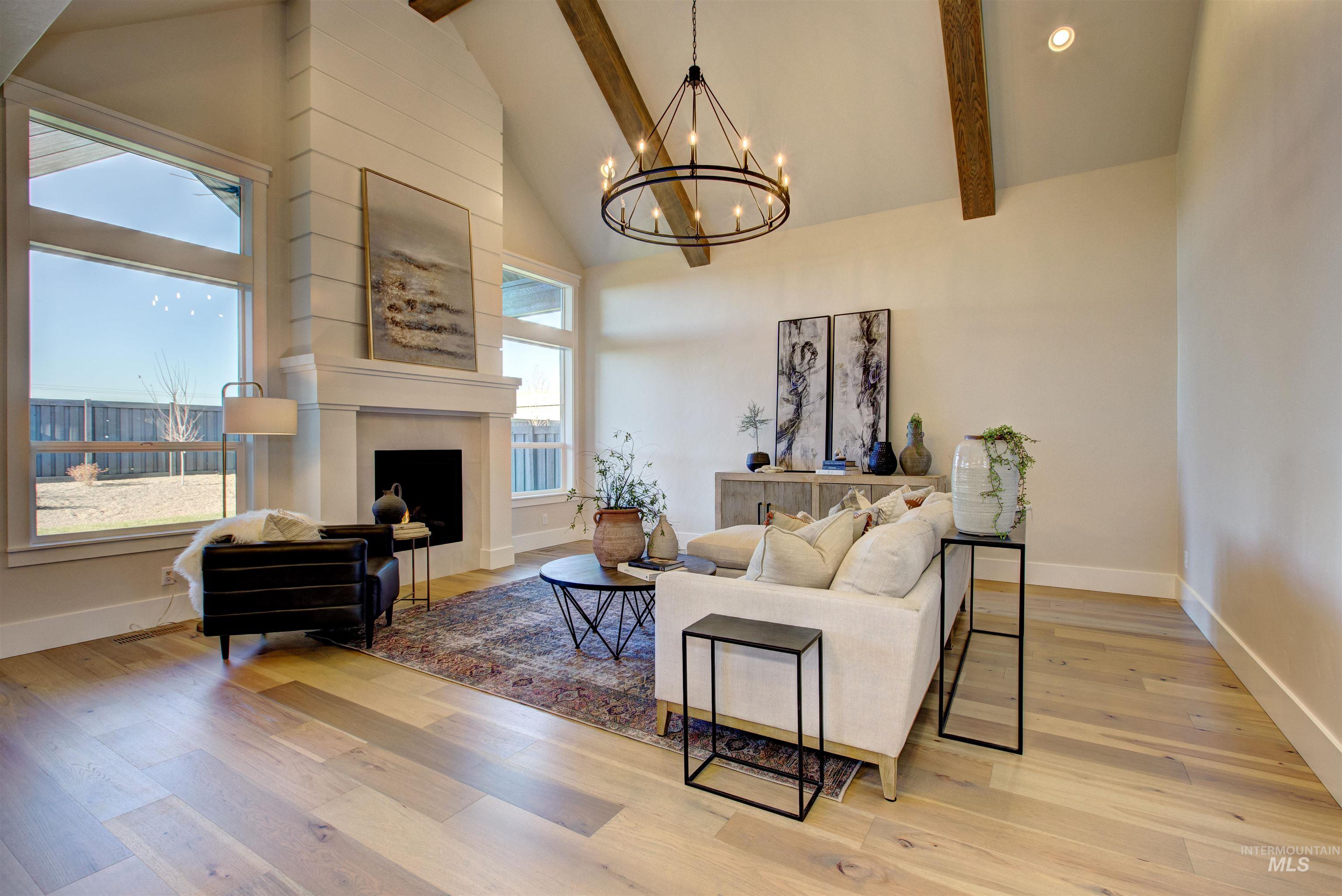 Living area with high vaulted ceiling, beamed ceiling, light wood-style floors, plenty of natural light, and a large fireplace