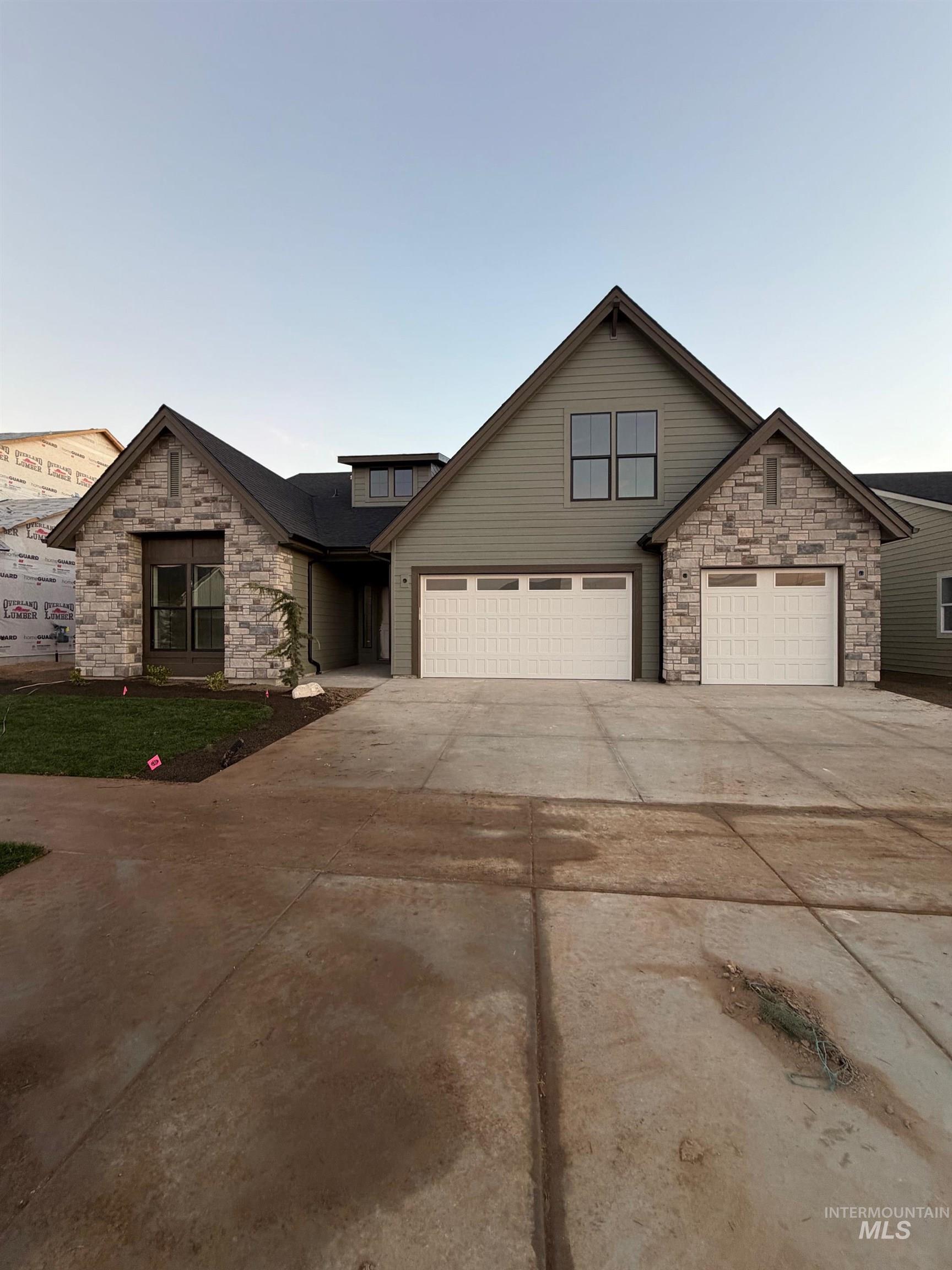 Traditional-style house with stone siding, concrete driveway, and an attached garage