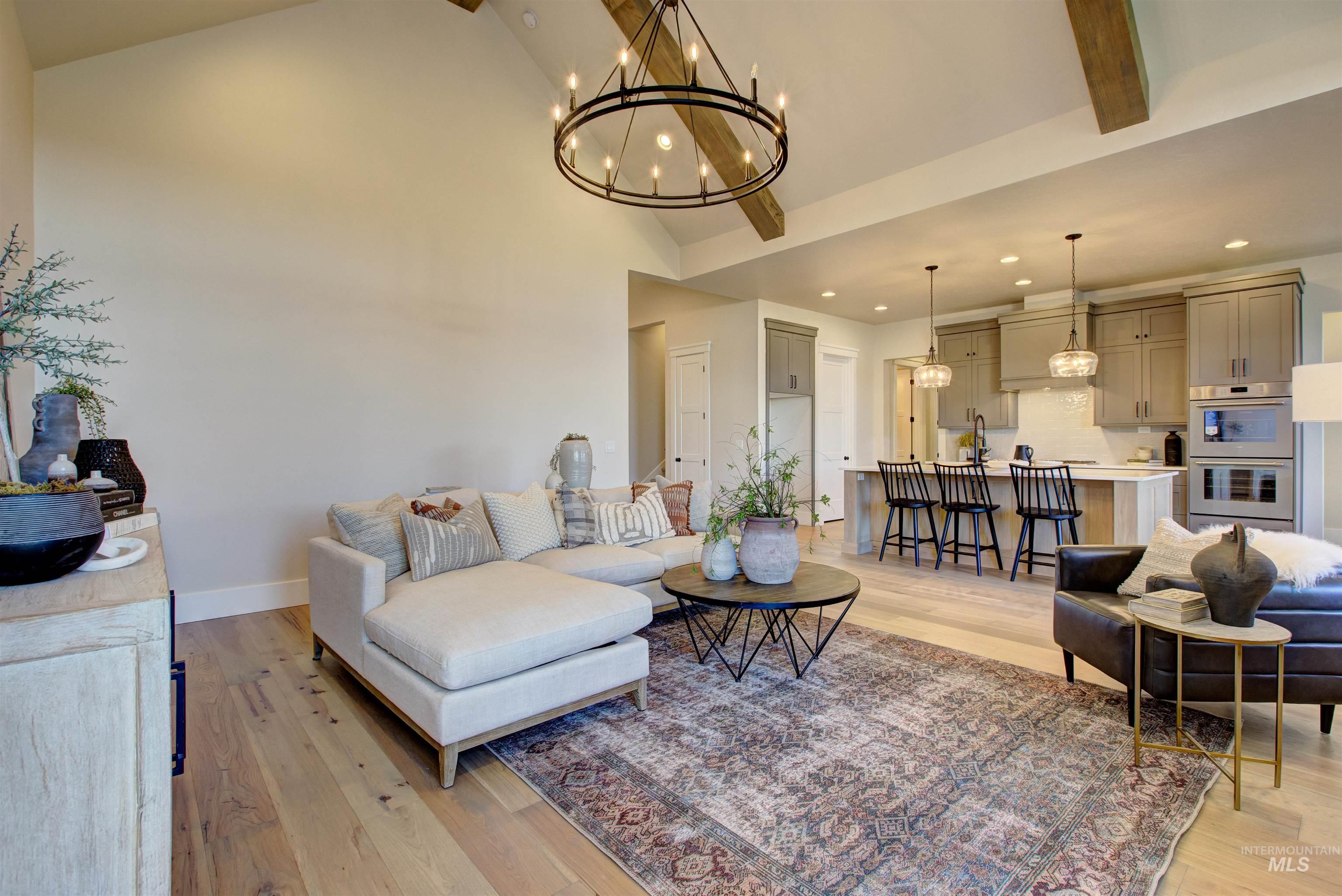 Living room featuring light wood-type flooring, a chandelier, high vaulted ceiling, beam ceiling, and recessed lighting