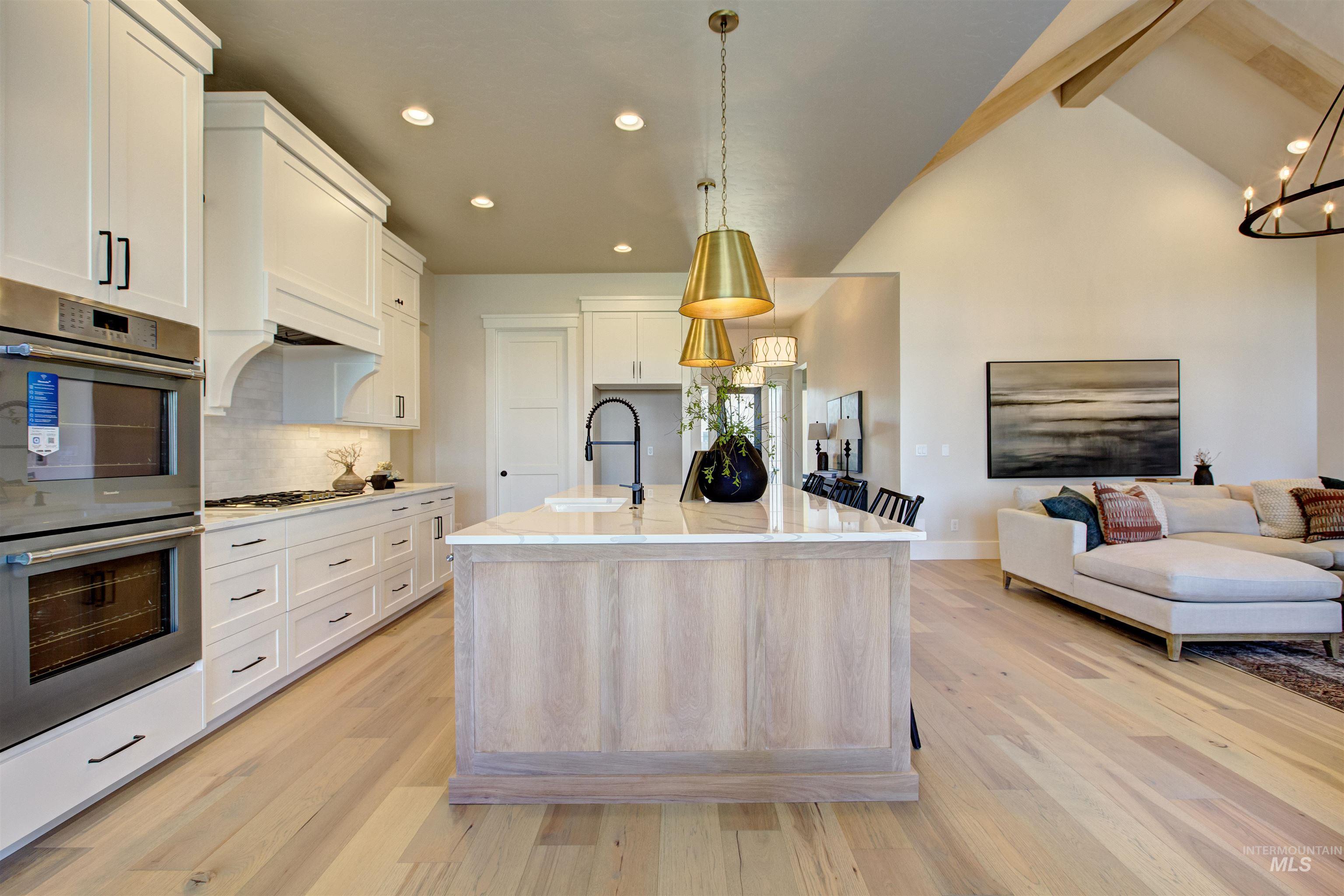 Kitchen featuring double oven, beam ceiling, tasteful backsplash, light wood finished floors, and recessed lighting