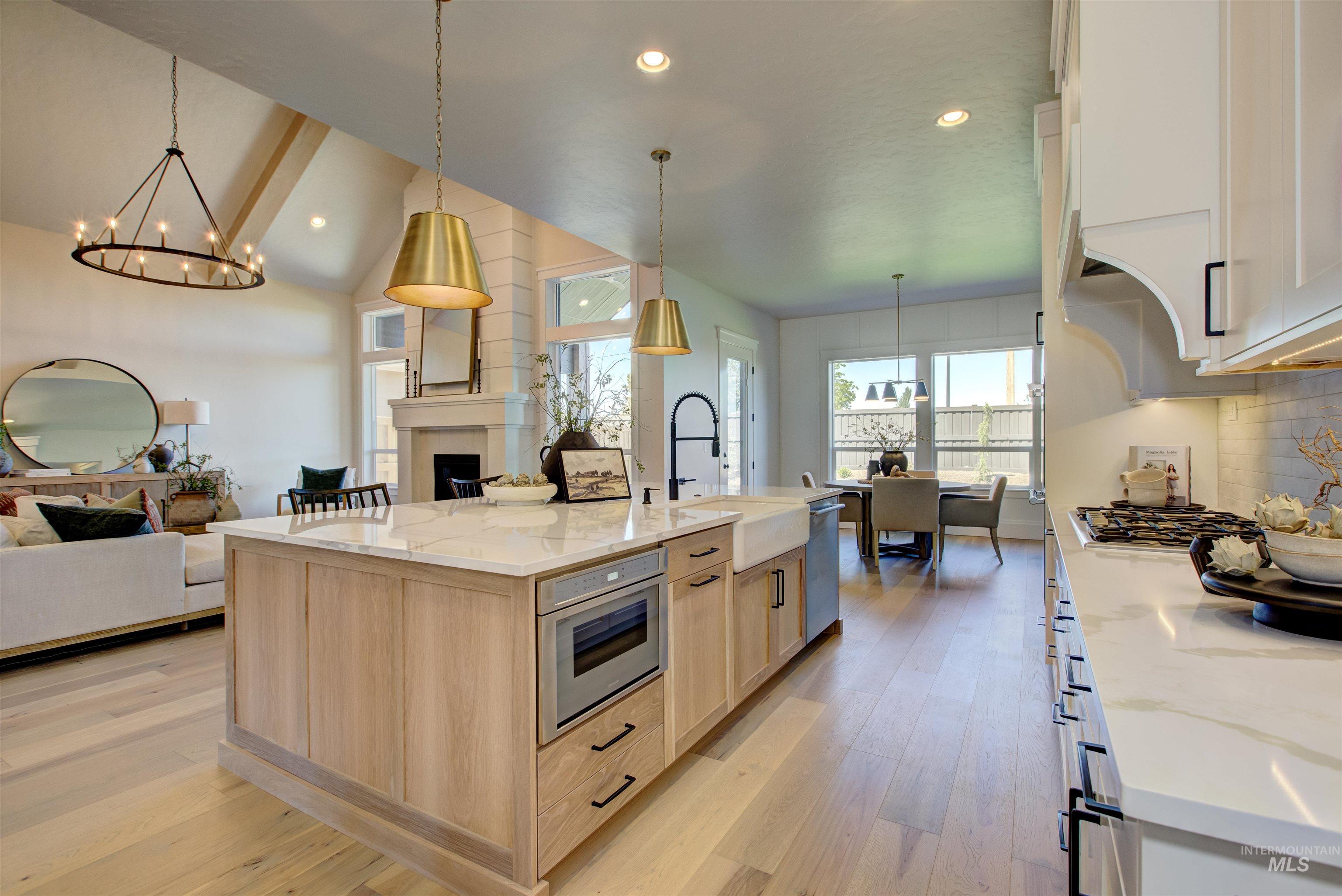 Kitchen with open floor plan, light brown cabinetry, a chandelier, decorative backsplash, and light stone counters