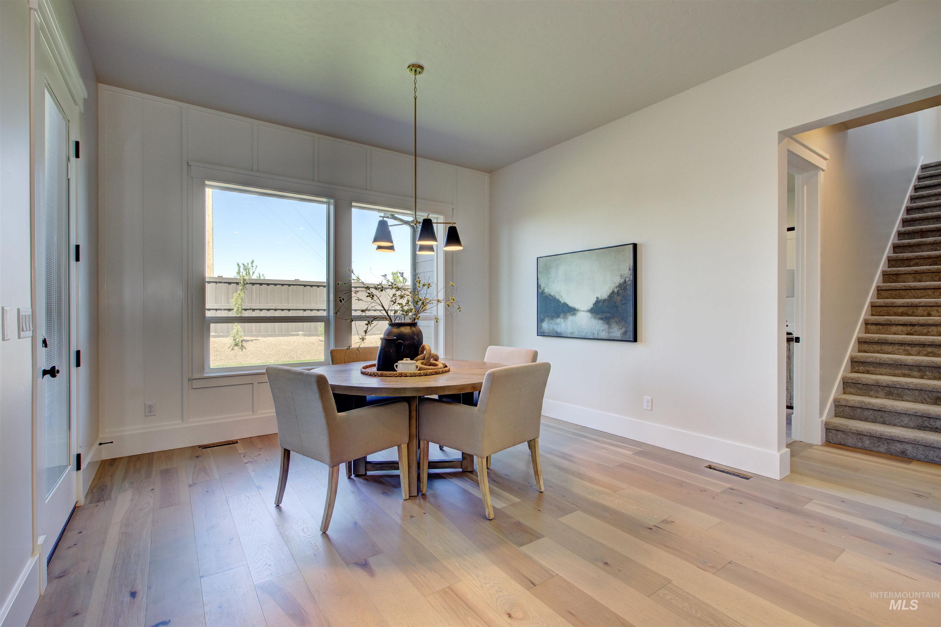 Dining space with stairs, light wood-style floors, and a chandelier