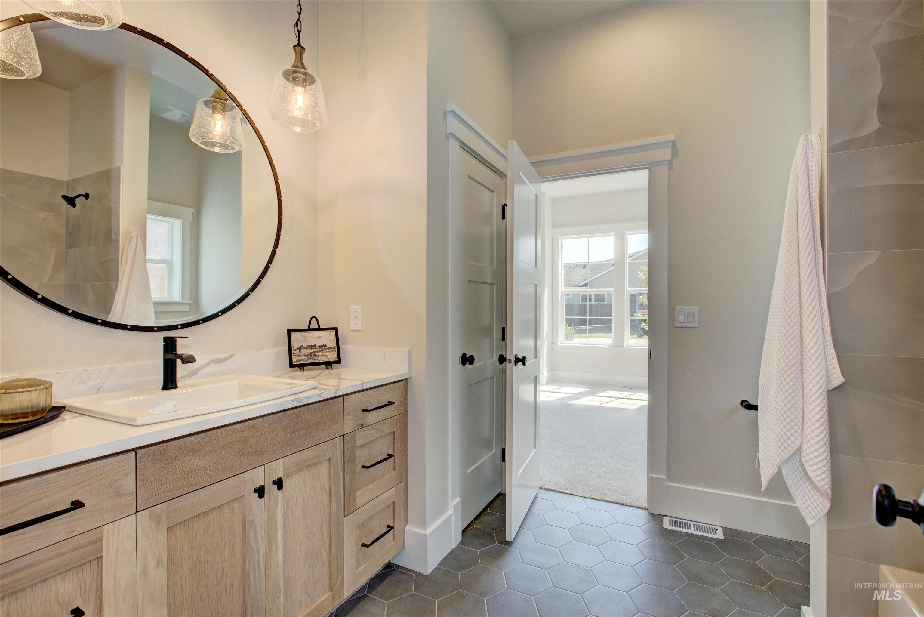 Bathroom with vanity, tile patterned flooring, and a shower