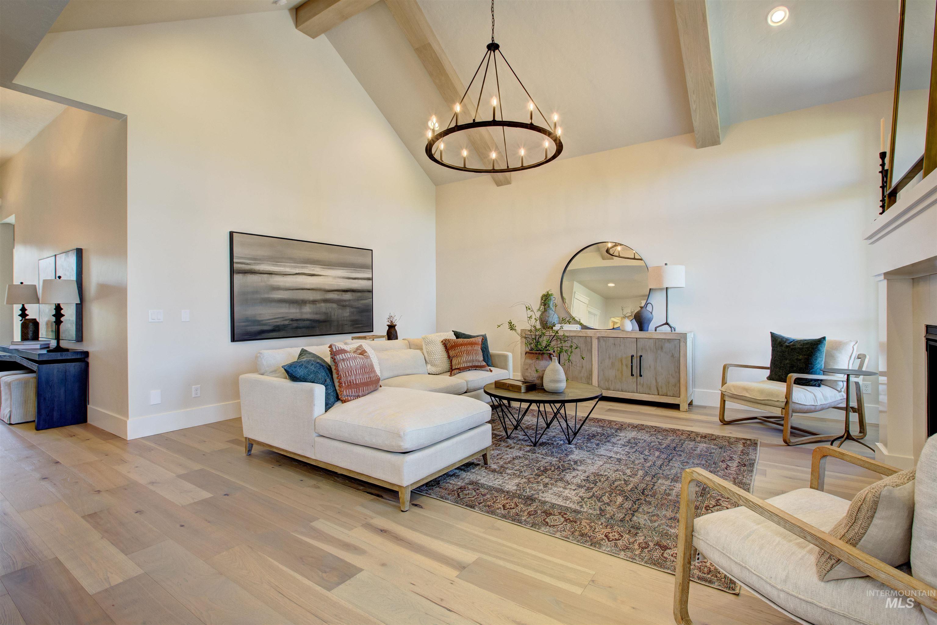 Living area with high vaulted ceiling, beam ceiling, wood finished floors, a chandelier, and a fireplace