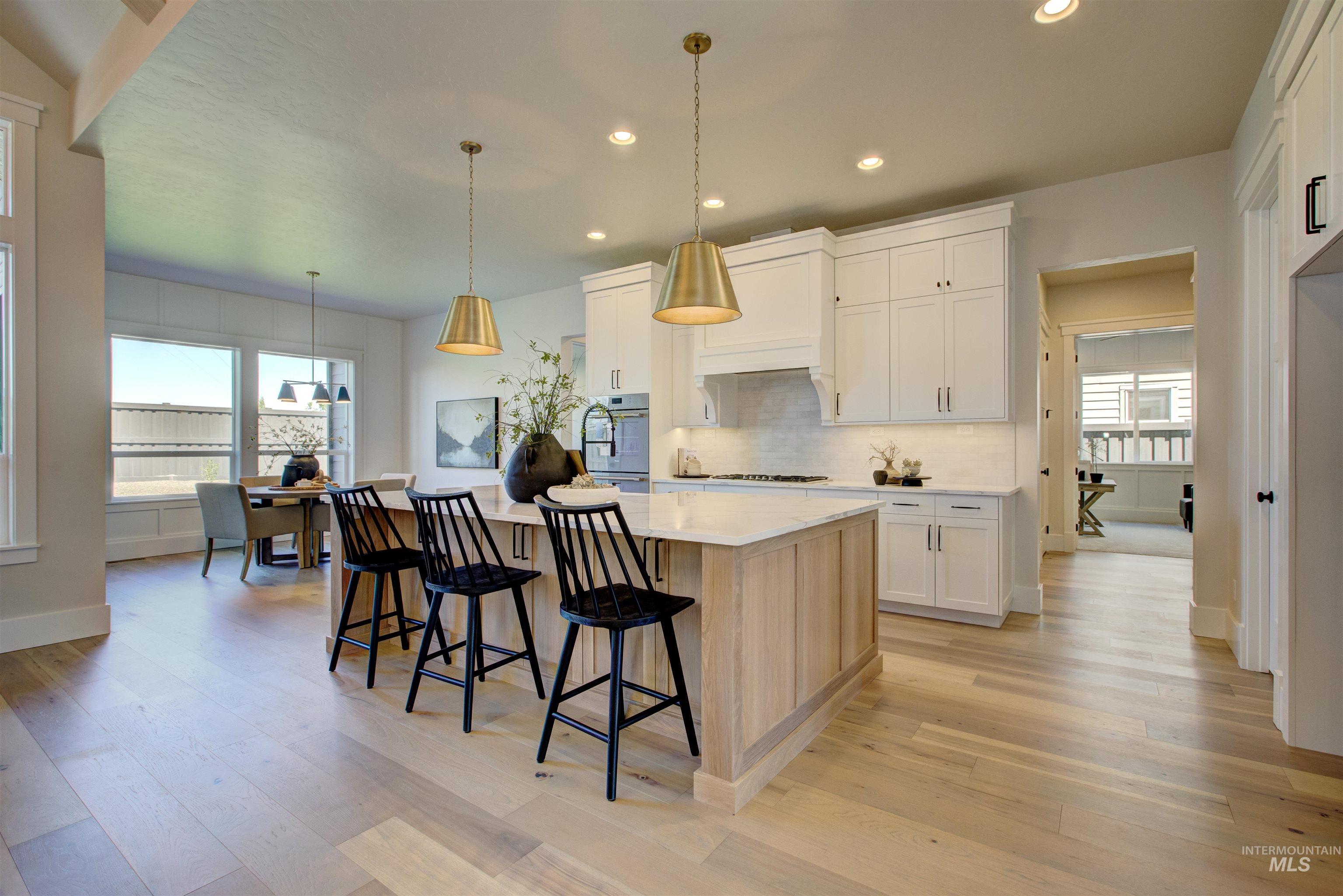Kitchen with backsplash, recessed lighting, light wood-style flooring, light countertops, and a breakfast bar