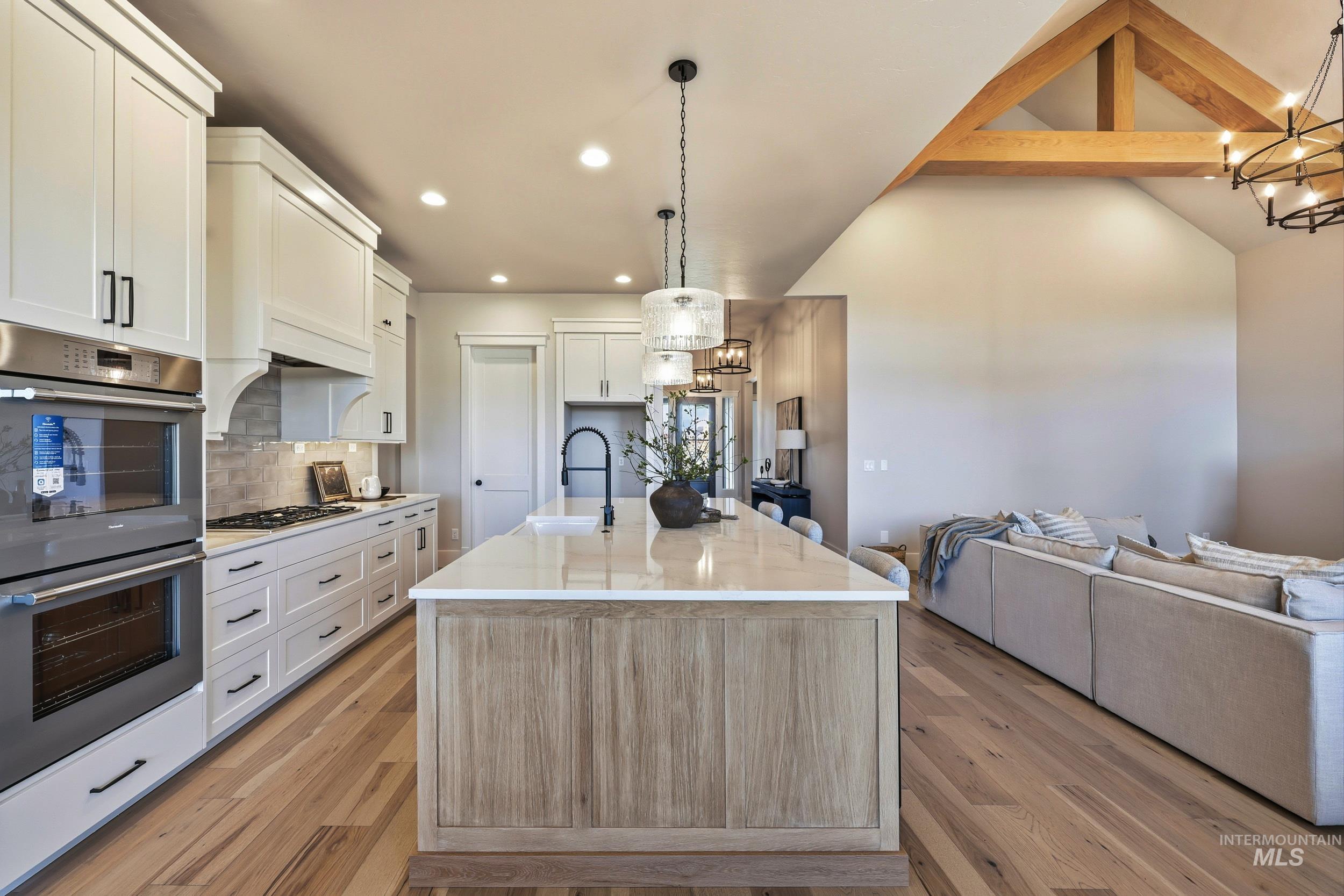 Kitchen featuring a chandelier, appliances with stainless steel finishes, backsplash, open floor plan, and decorative light fixtures