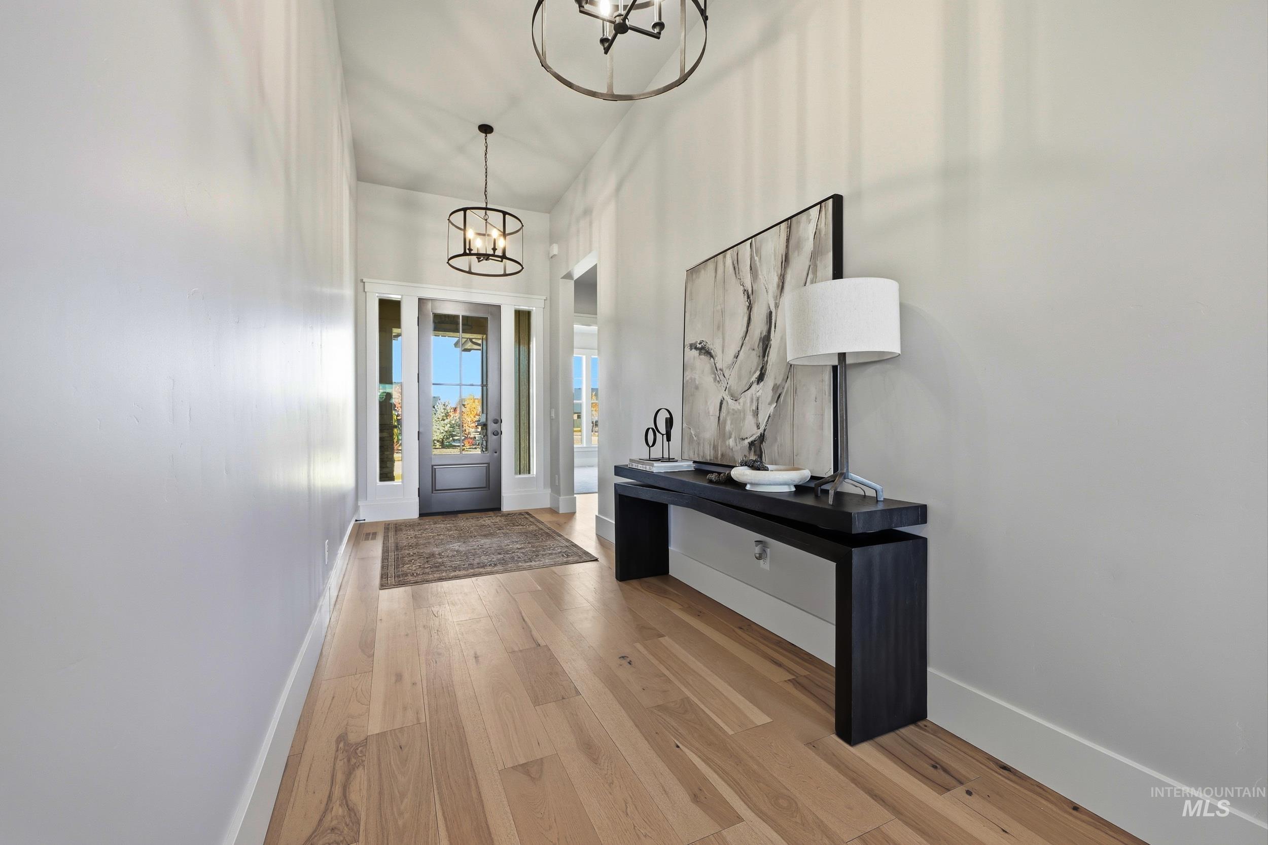 Foyer with light wood-style flooring and a chandelier