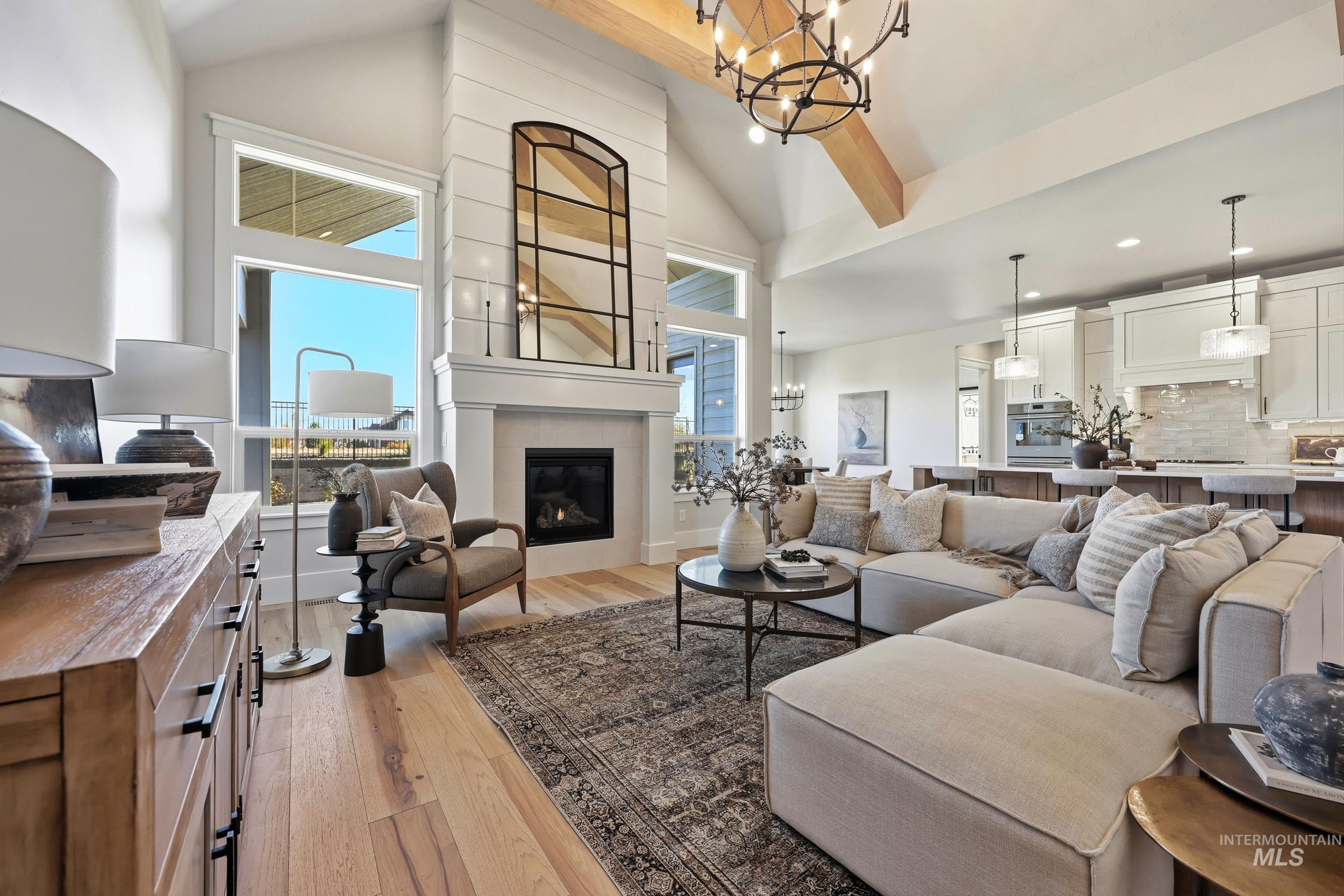 Living area featuring a chandelier, light wood-style floors, high vaulted ceiling, and a fireplace