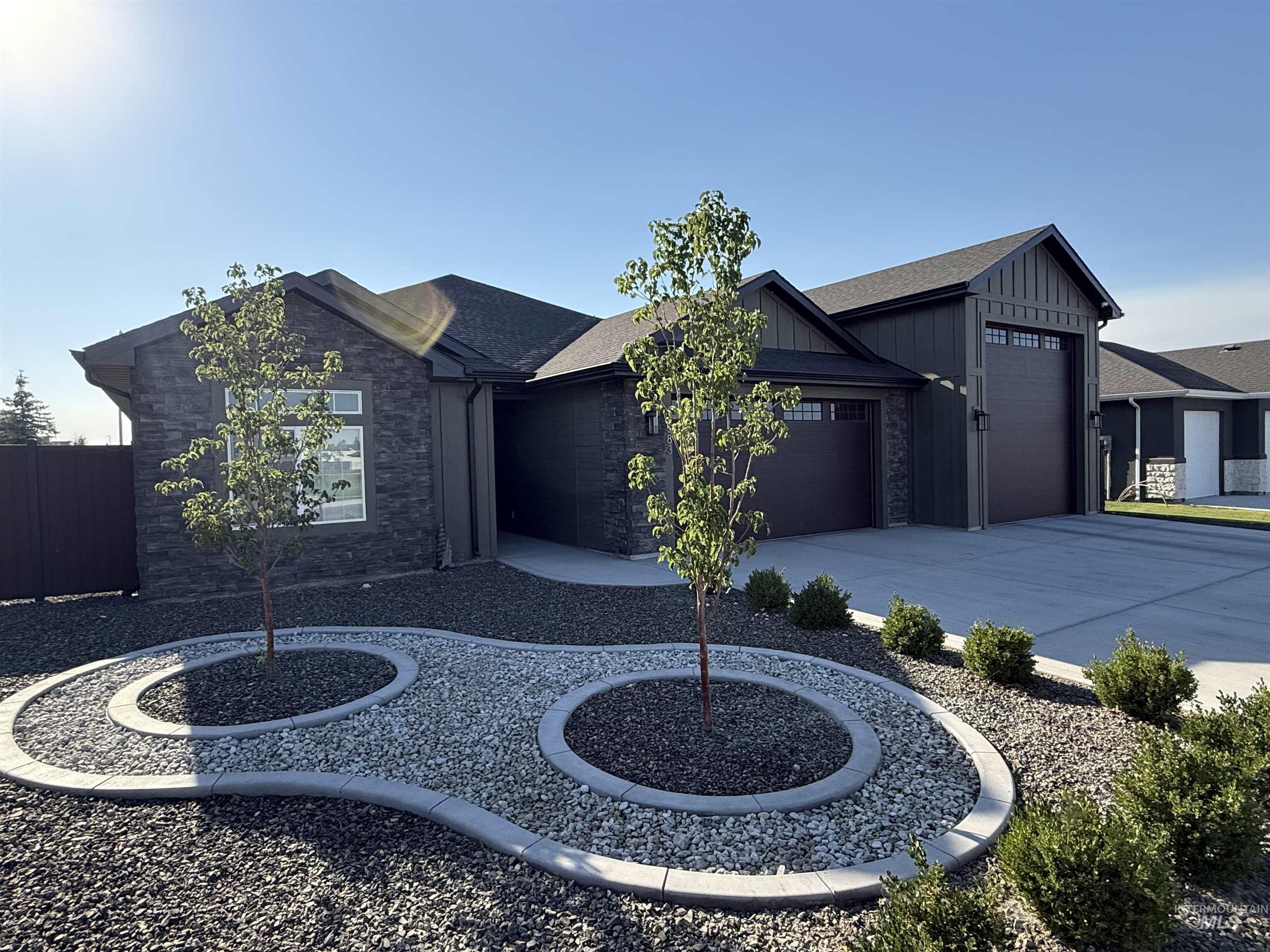 View of front of property featuring board and batten siding, concrete driveway, a garage, and stone siding
