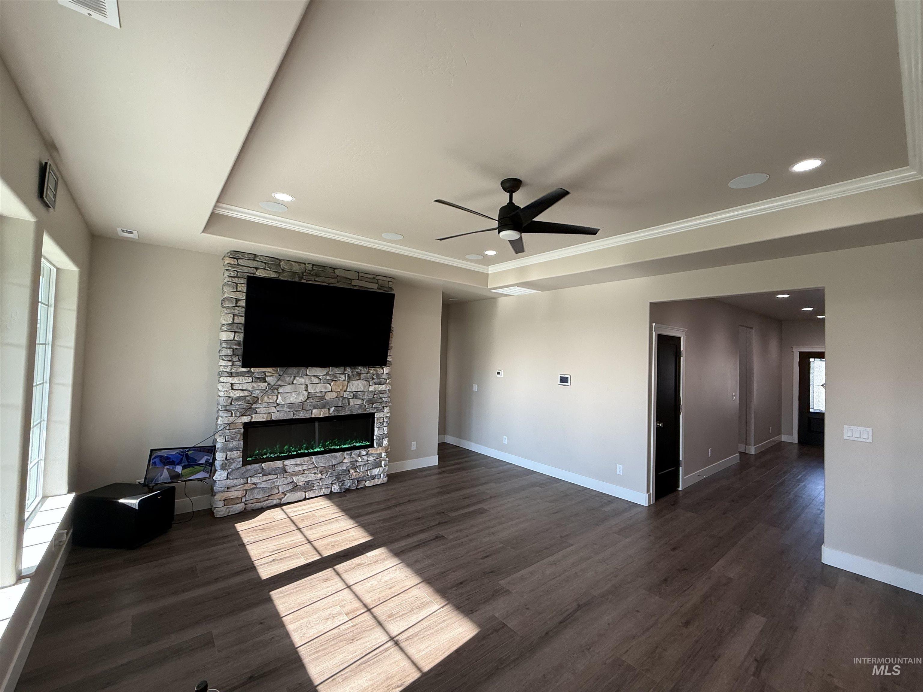 Unfurnished living room featuring ceiling fan, a fireplace, dark wood-style flooring, recessed lighting, and ornamental molding