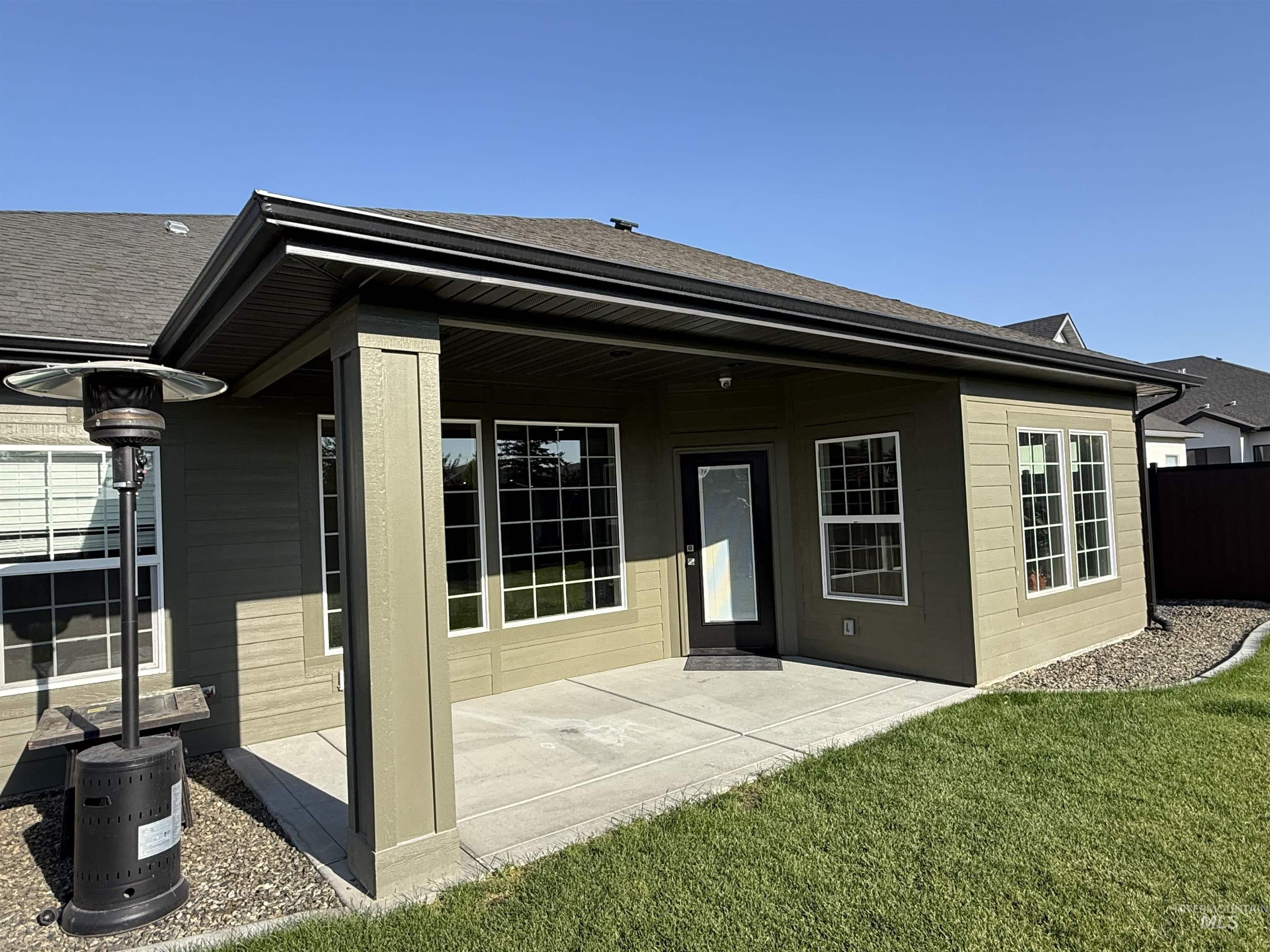 Back of property featuring a patio, a shingled roof, and a lawn