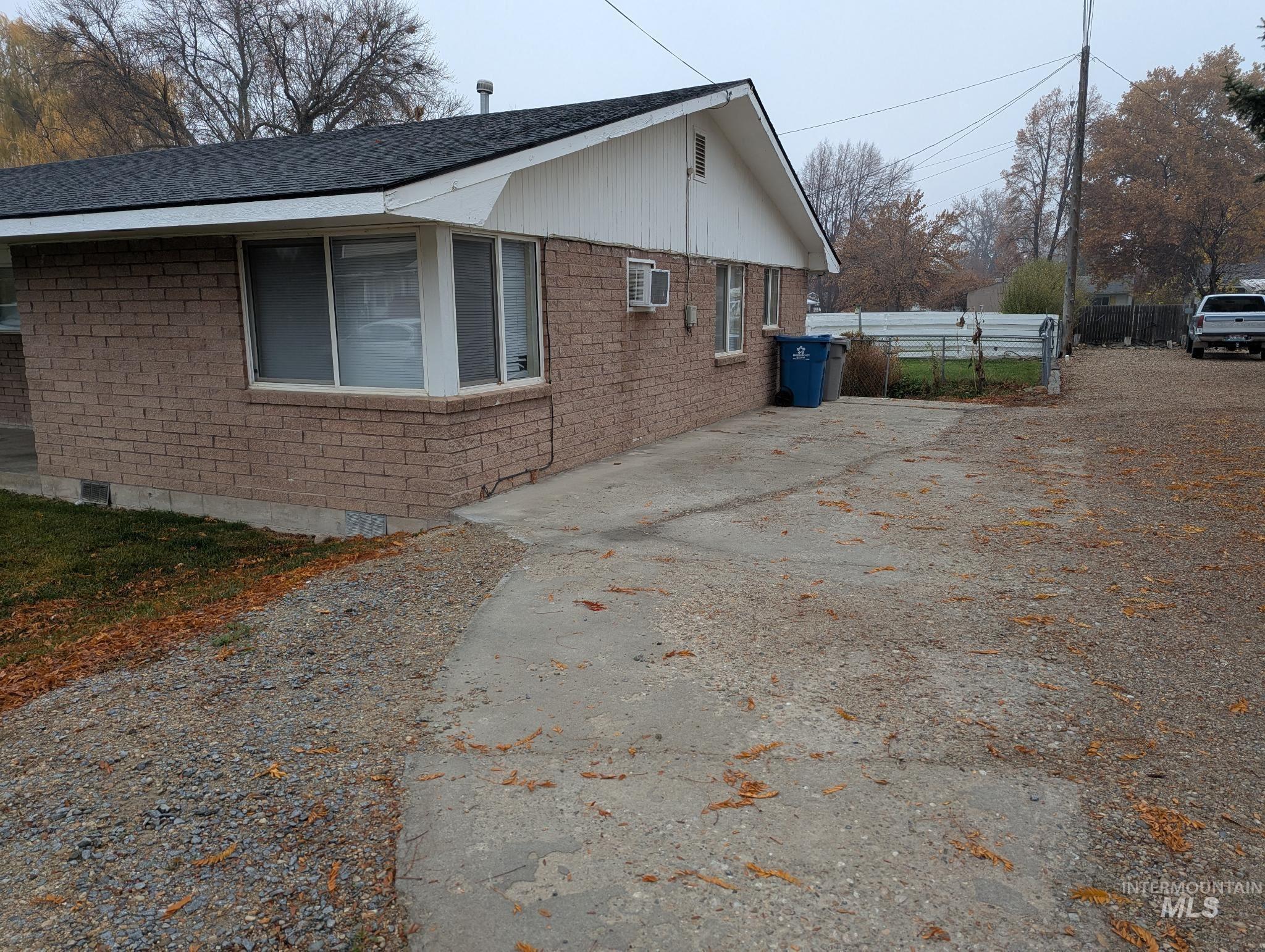 View of side of home featuring brick siding, roof with shingles, and driveway