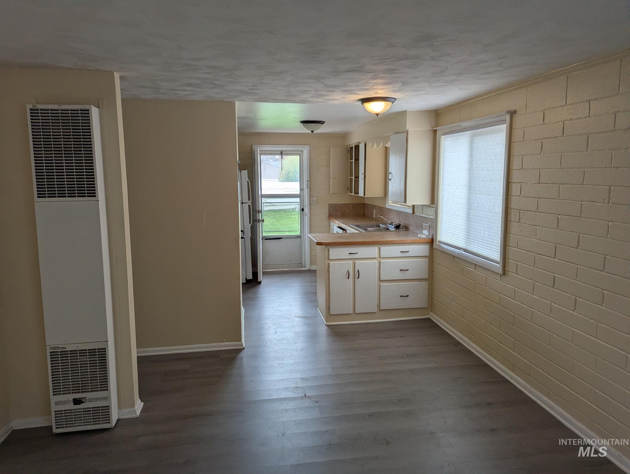 Kitchen with light countertops, a heating unit, healthy amount of natural light, and dark wood-type flooring