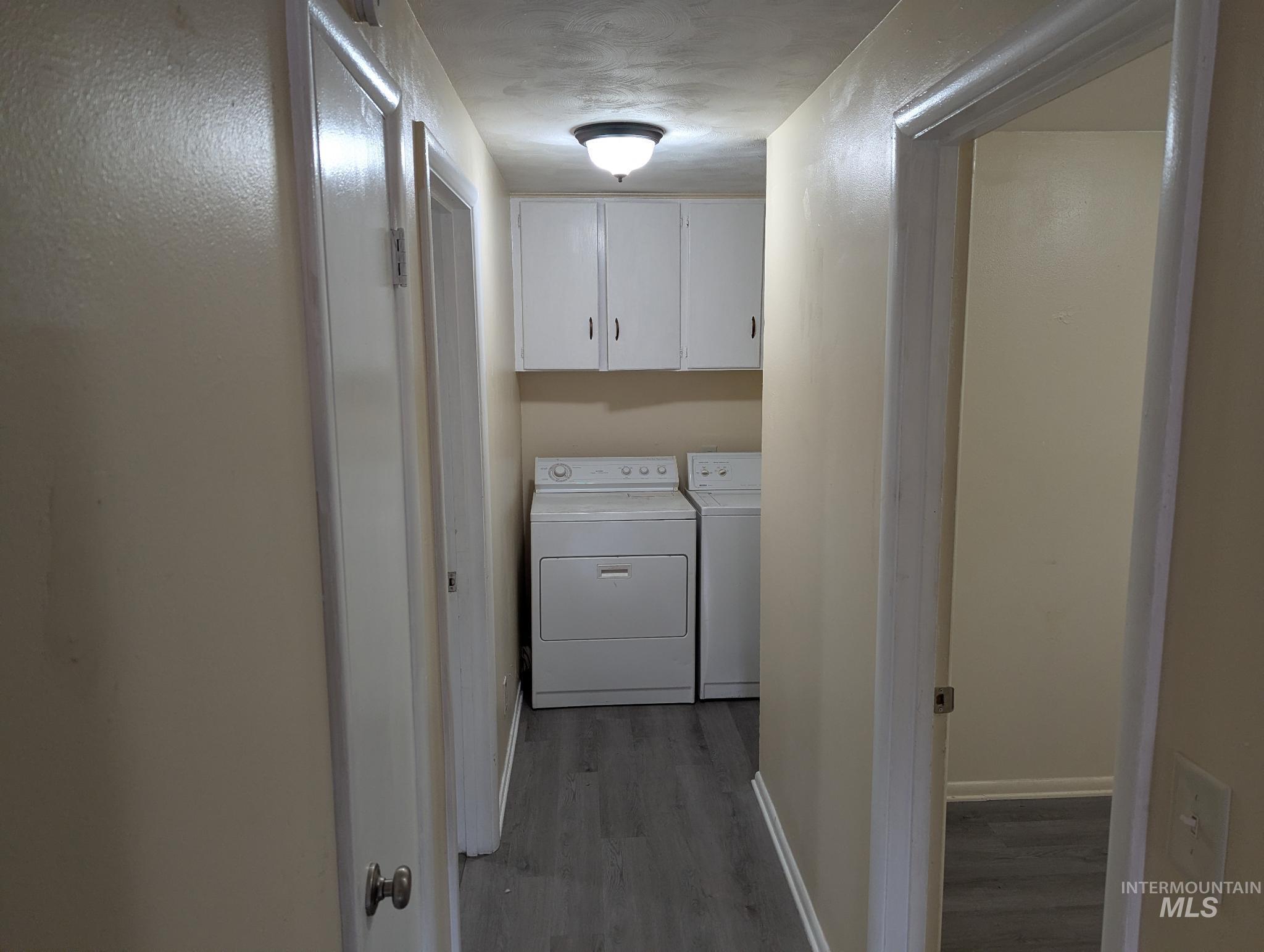 Laundry area featuring light wood finished floors, separate washer and dryer, and cabinet space