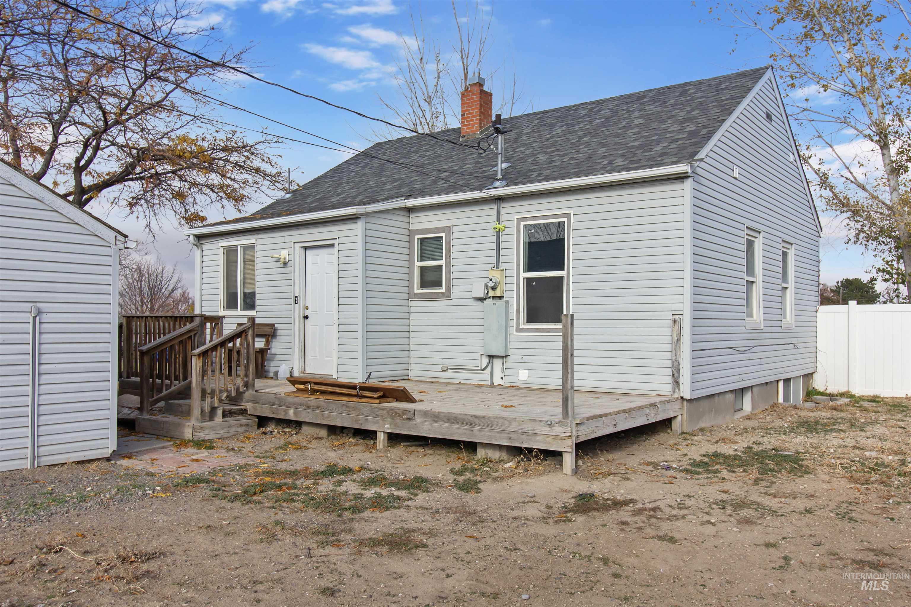 Back of house with a chimney, roof with shingles, and a deck