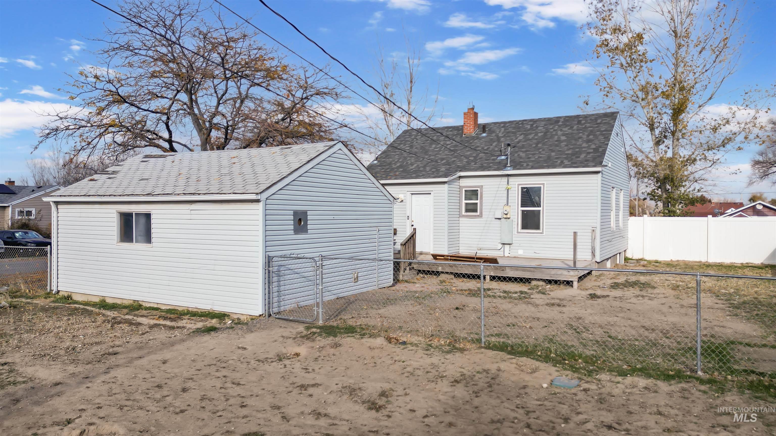 Back of house featuring a wooden deck, a fenced backyard, a chimney, and roof with shingles