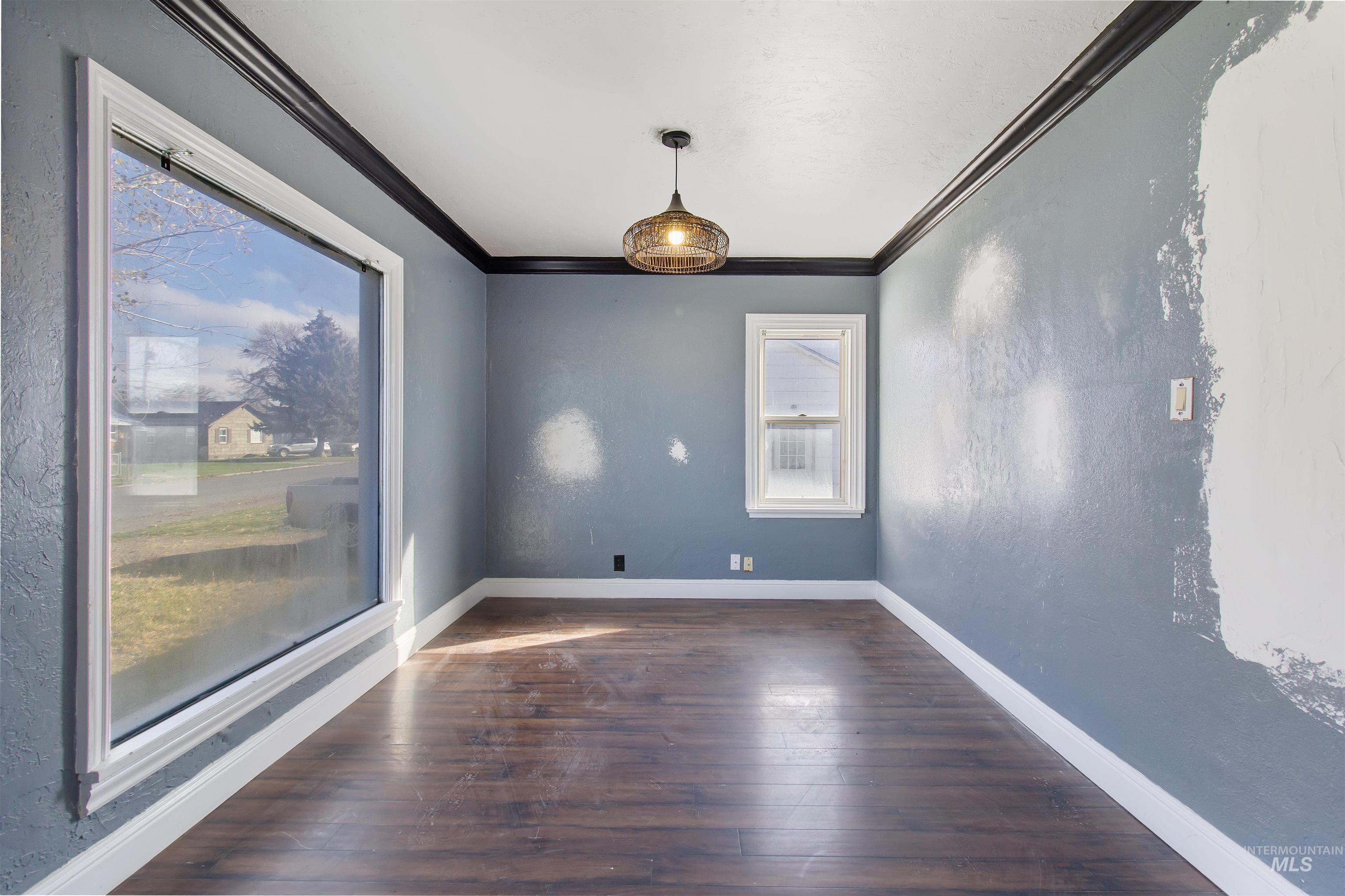Empty room with ornamental molding, a textured wall, and dark wood-style floors