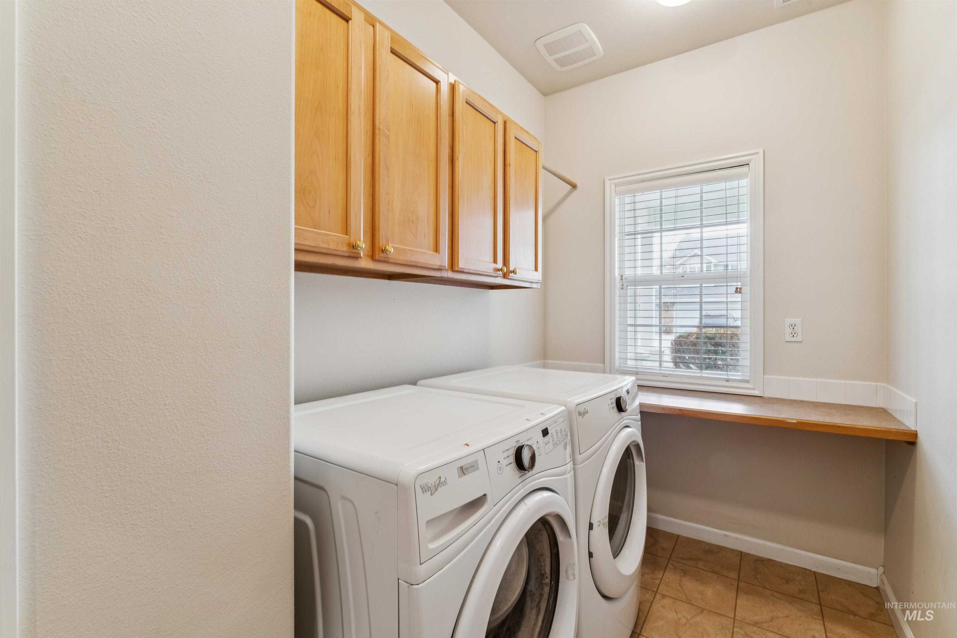 Washroom featuring cabinet space, washing machine and clothes dryer, and light tile patterned flooring