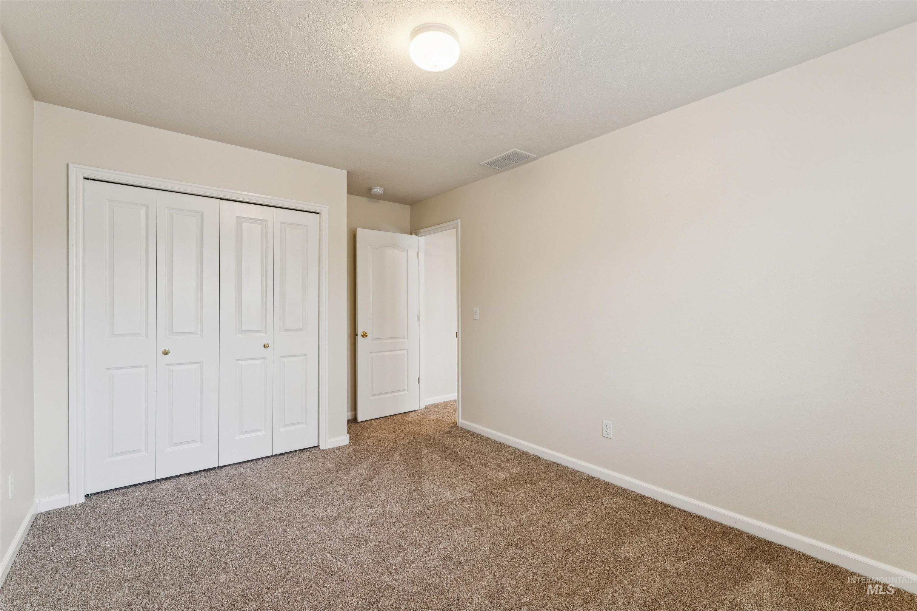 Unfurnished bedroom with carpet, a closet, and a textured ceiling