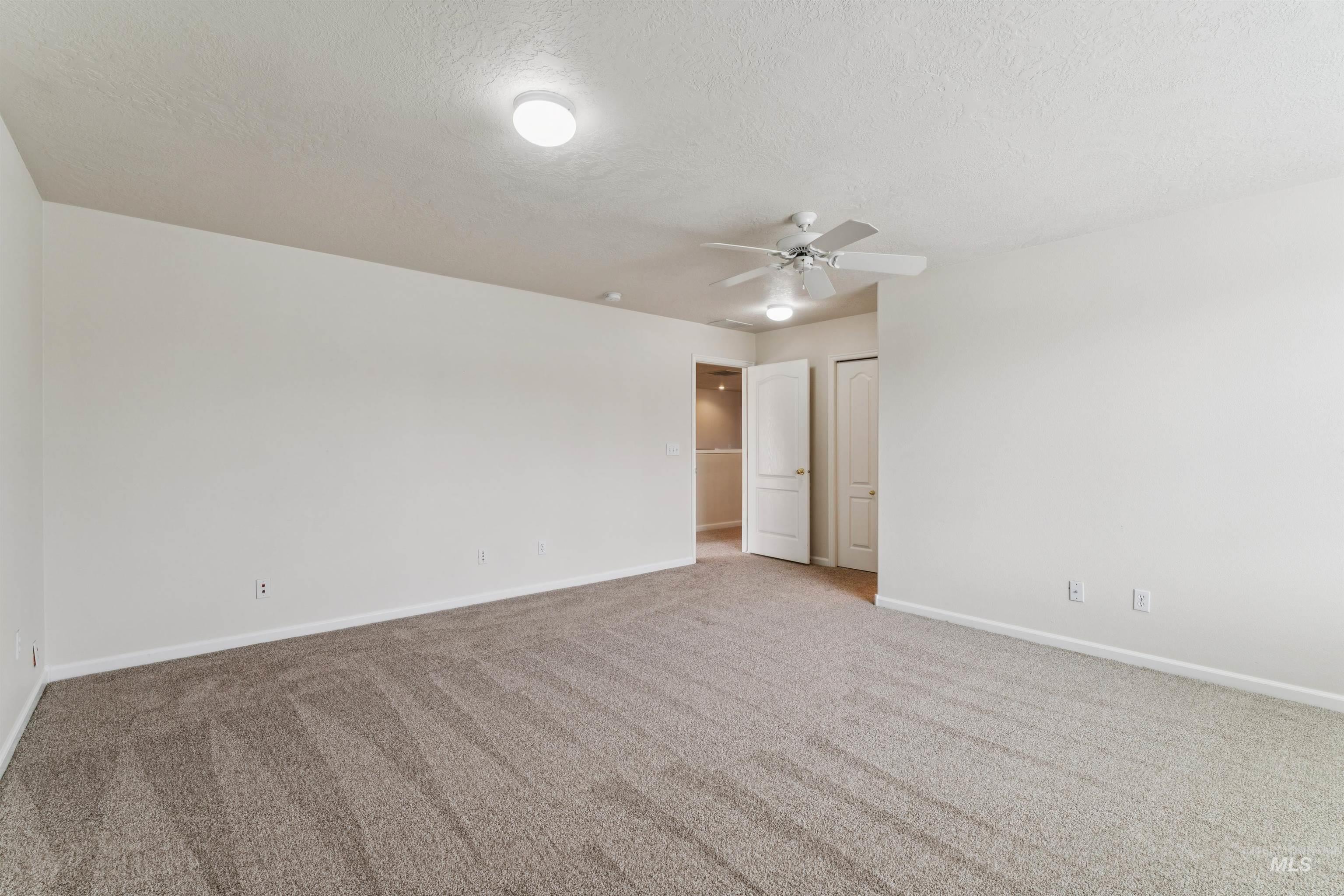 Unfurnished bedroom featuring a textured ceiling, carpet floors, and a ceiling fan