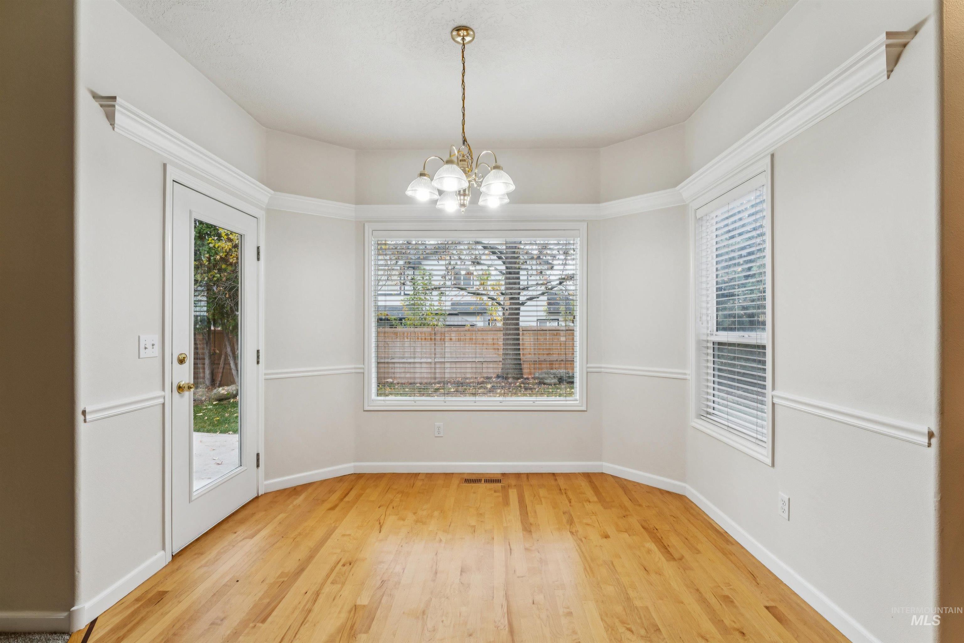 Unfurnished dining area with light wood-type flooring and a chandelier
