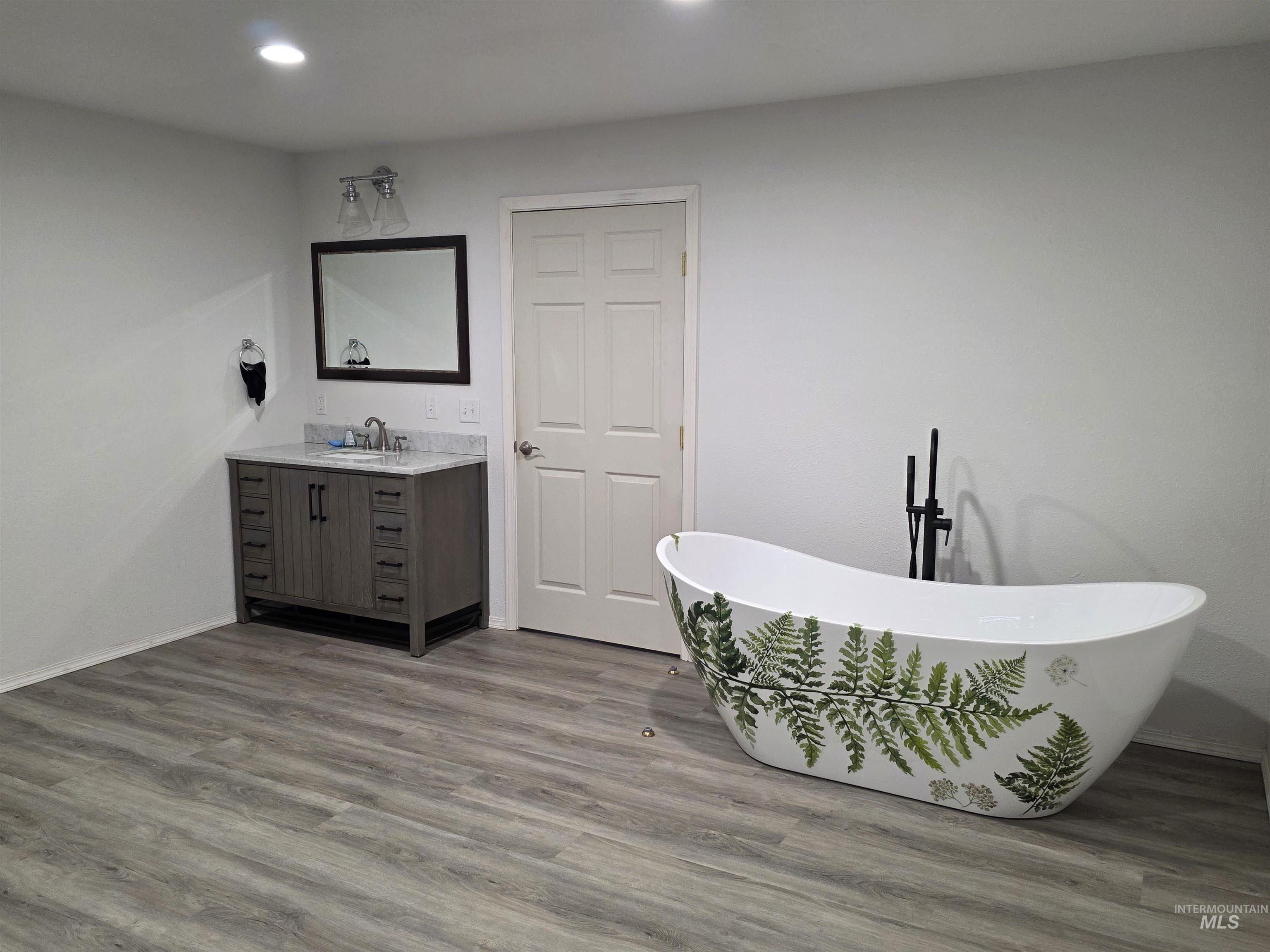 Bathroom with vanity, a freestanding tub, dark wood-style floors, and recessed lighting