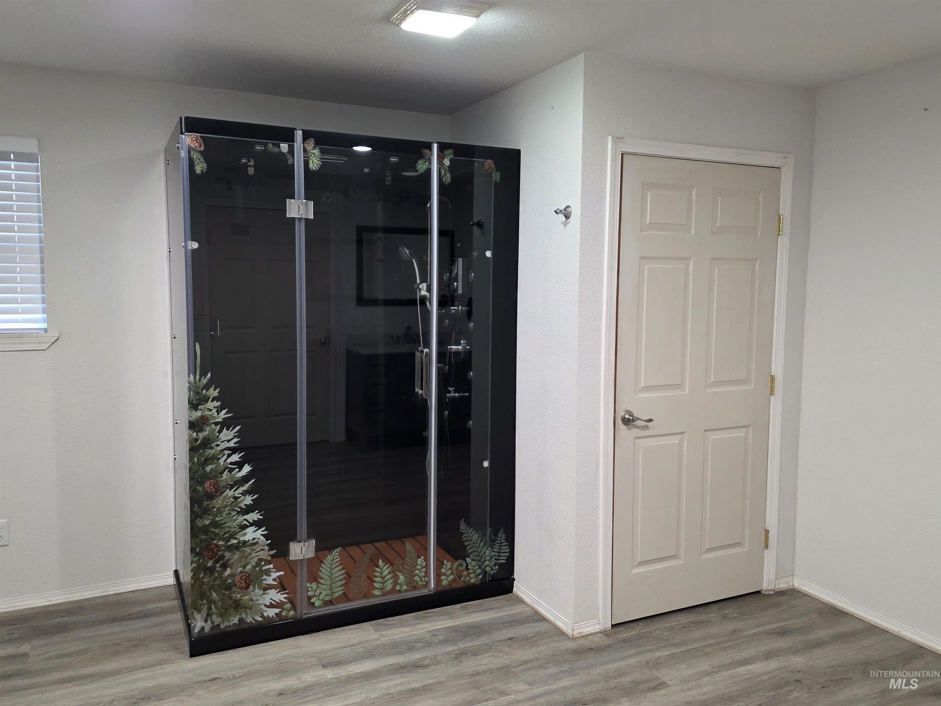 Bathroom featuring light wood-type flooring and a shower stall