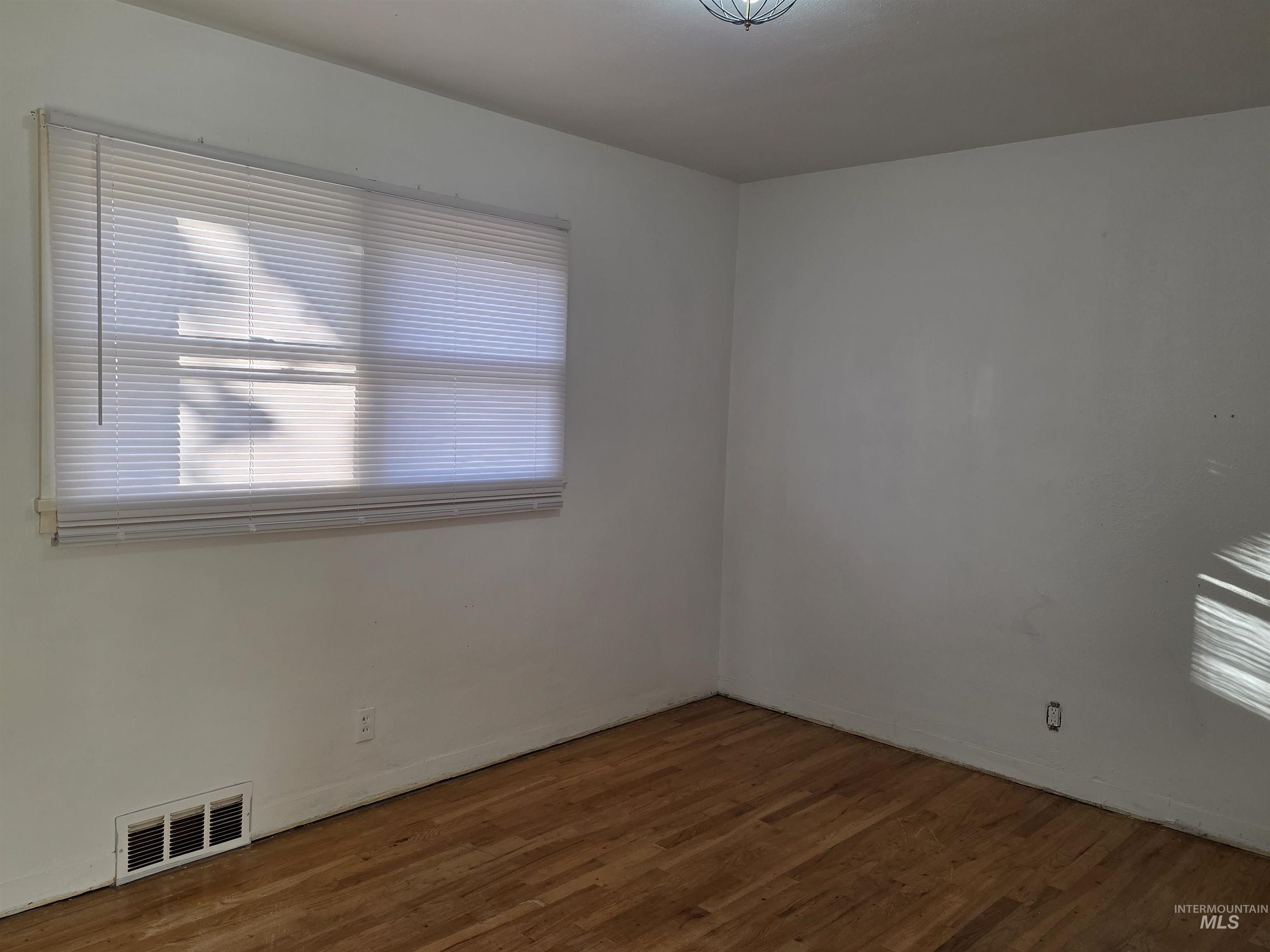 Spare room featuring healthy amount of natural light and wood finished floors