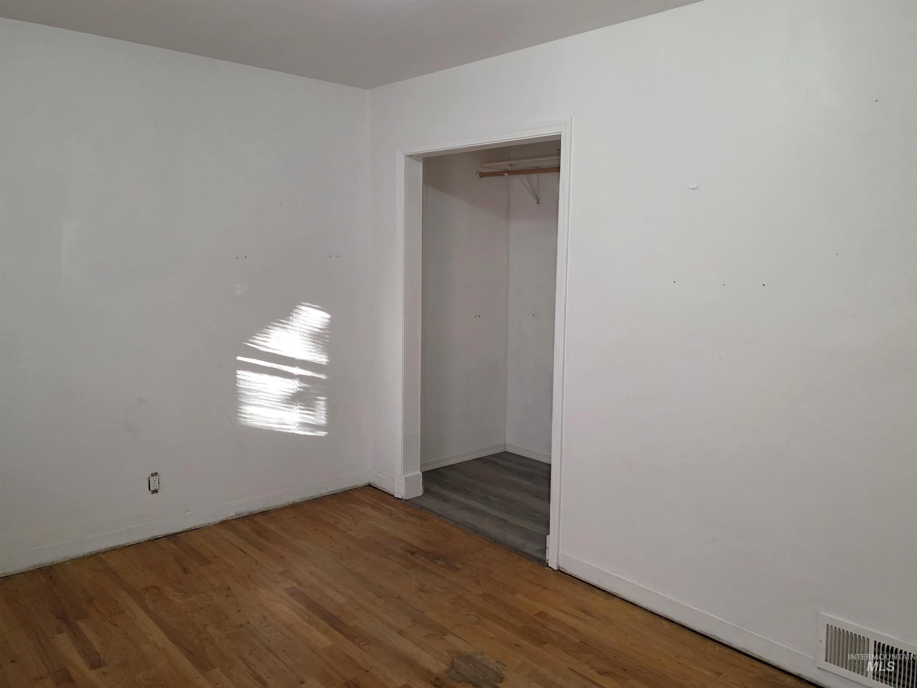 Unfurnished bedroom with wood finished floors and a closet